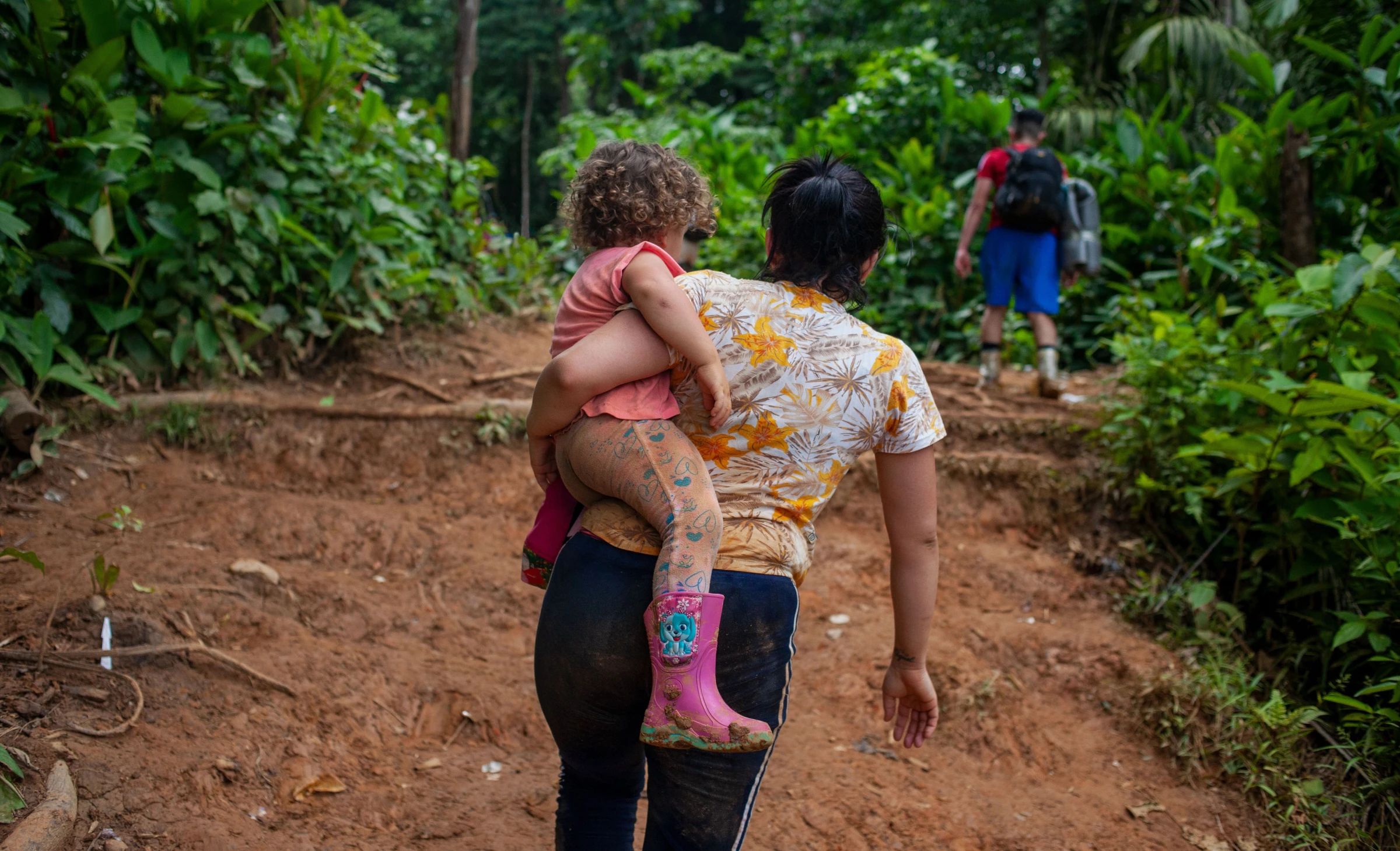 Venezuelan migrant Macyuli, traveling with her four children and husband, and other Venezuelan families, walks along the jungle path through the Darién Gap carrying her daughter. Darién Gap, Colombia, July 27, 2022. Thomson Reuters Foundation/Fabio Cuttica