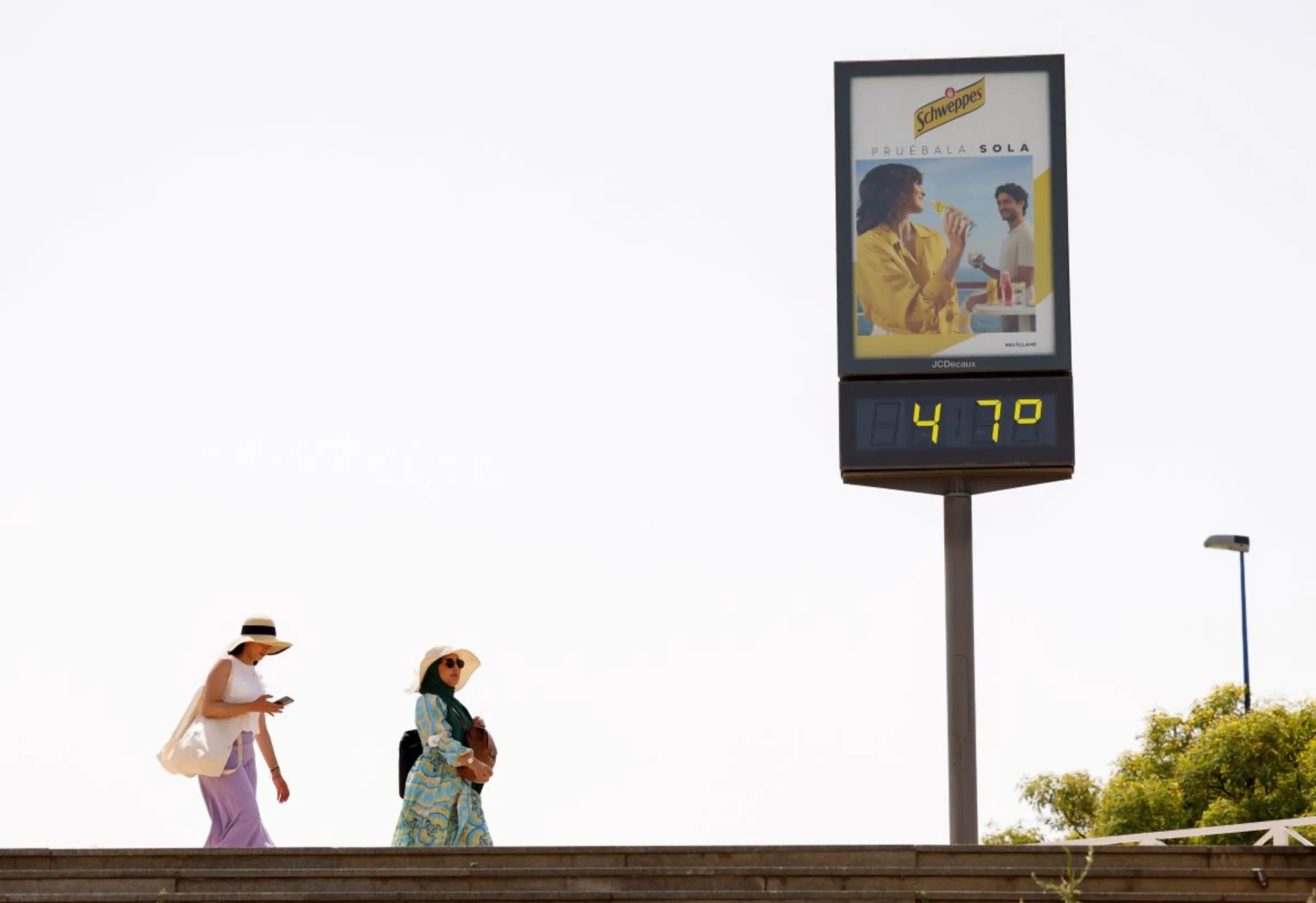 Women walk next to a thermometer displaying 47 Celsius degrees (116.6 Fahrenheit degrees) during the first heatwave of the year in Seville, Spain June 11, 2022