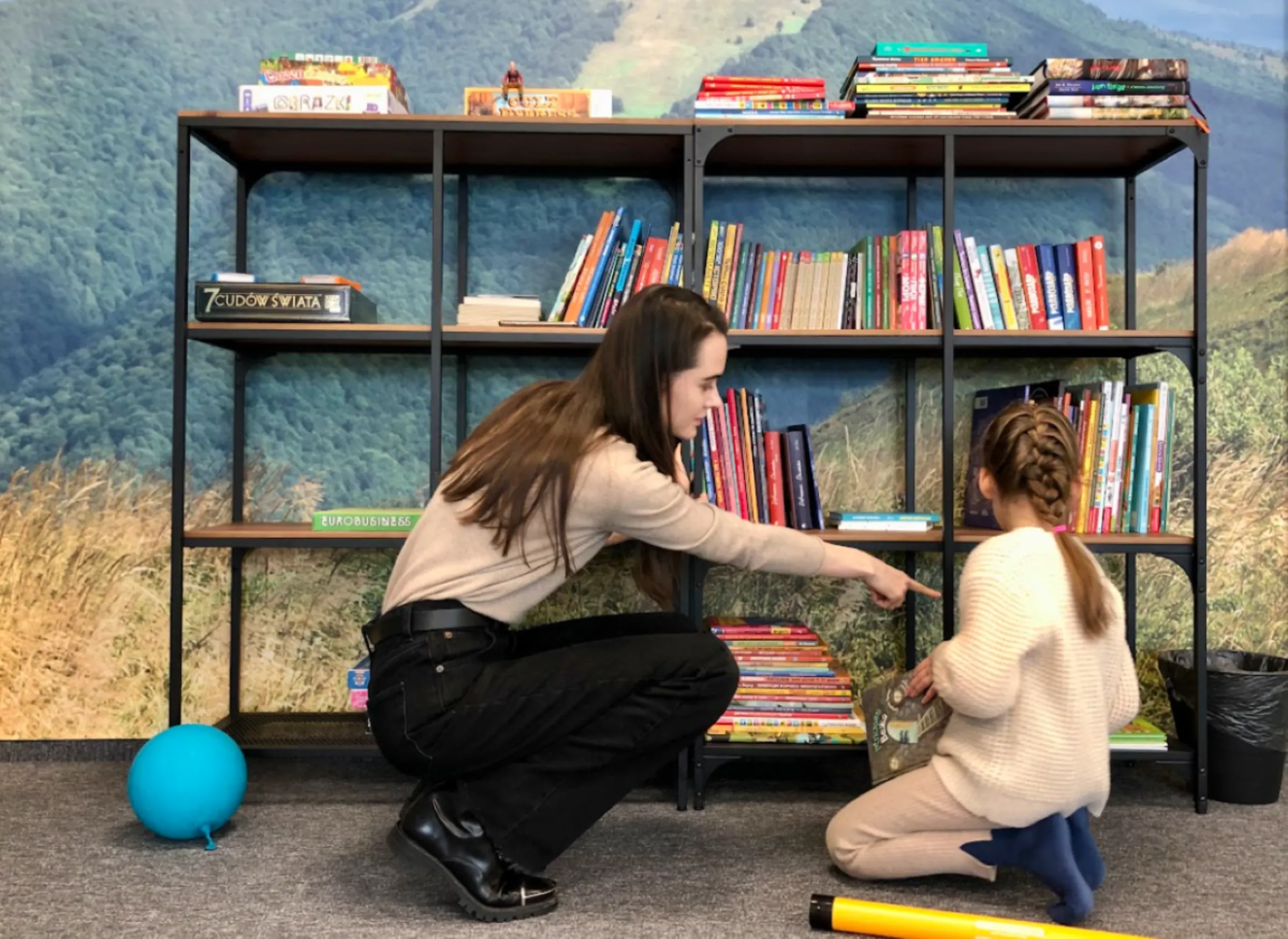 Kateryna Yuspina selects a book to read with her six-year-old daughter at a drop-in centre in Rzeszów, Poland February 24, 2023