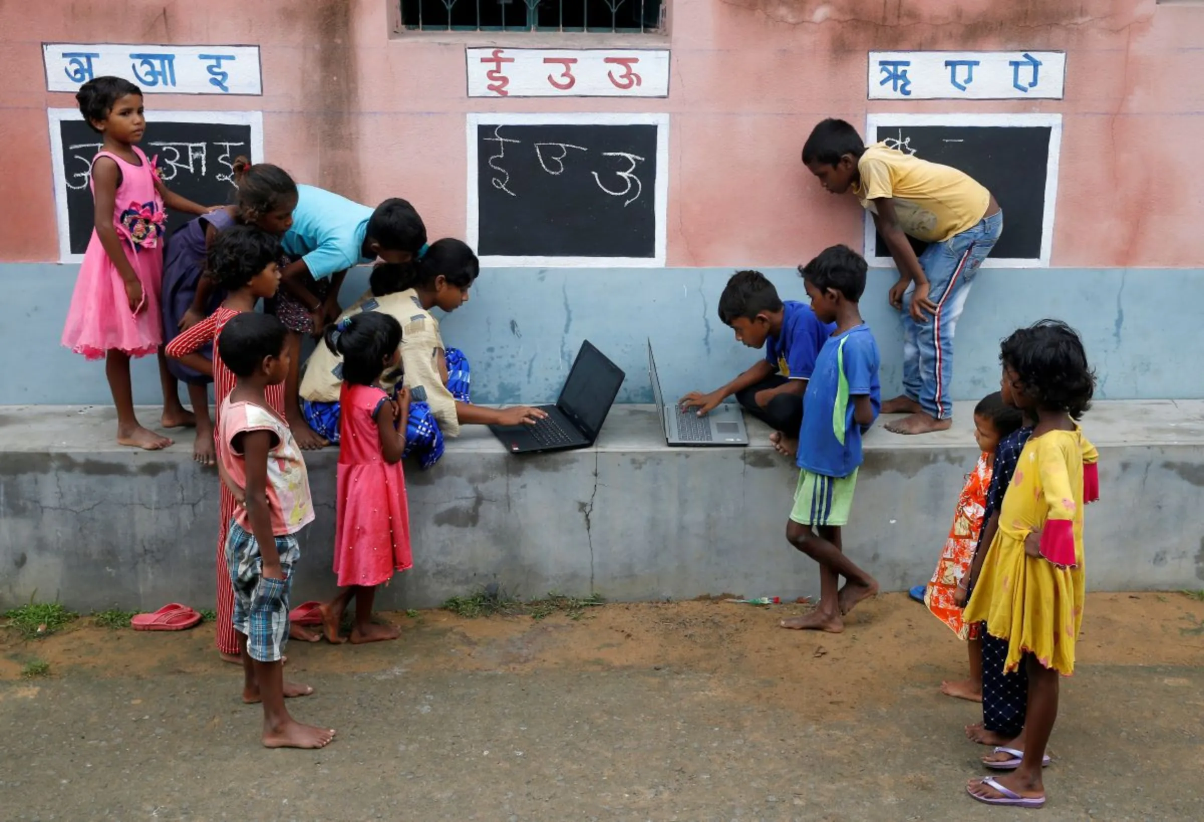 Children, who do not have access to internet facilities and gadgets, use laptops in an open-air class outside a house with the walls converted into black boards, at Joba Attpara village in Paschim Bardhaman district in the eastern state of West Bengal, India, September 13, 2021