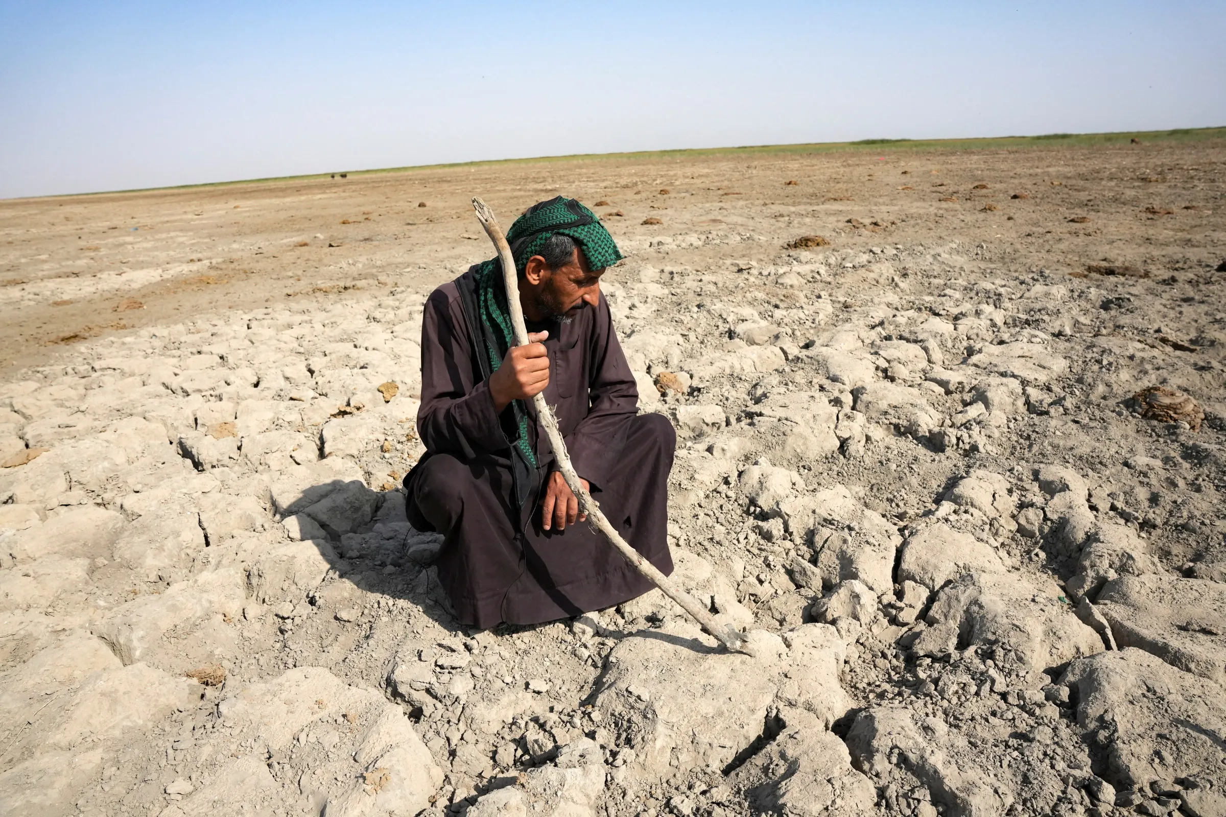 An Iraqi Marsh Arab man looks at dry ground that was previously covered with water at the Chebayesh marsh in Dhi Qar province, Iraq, June 3, 2022.