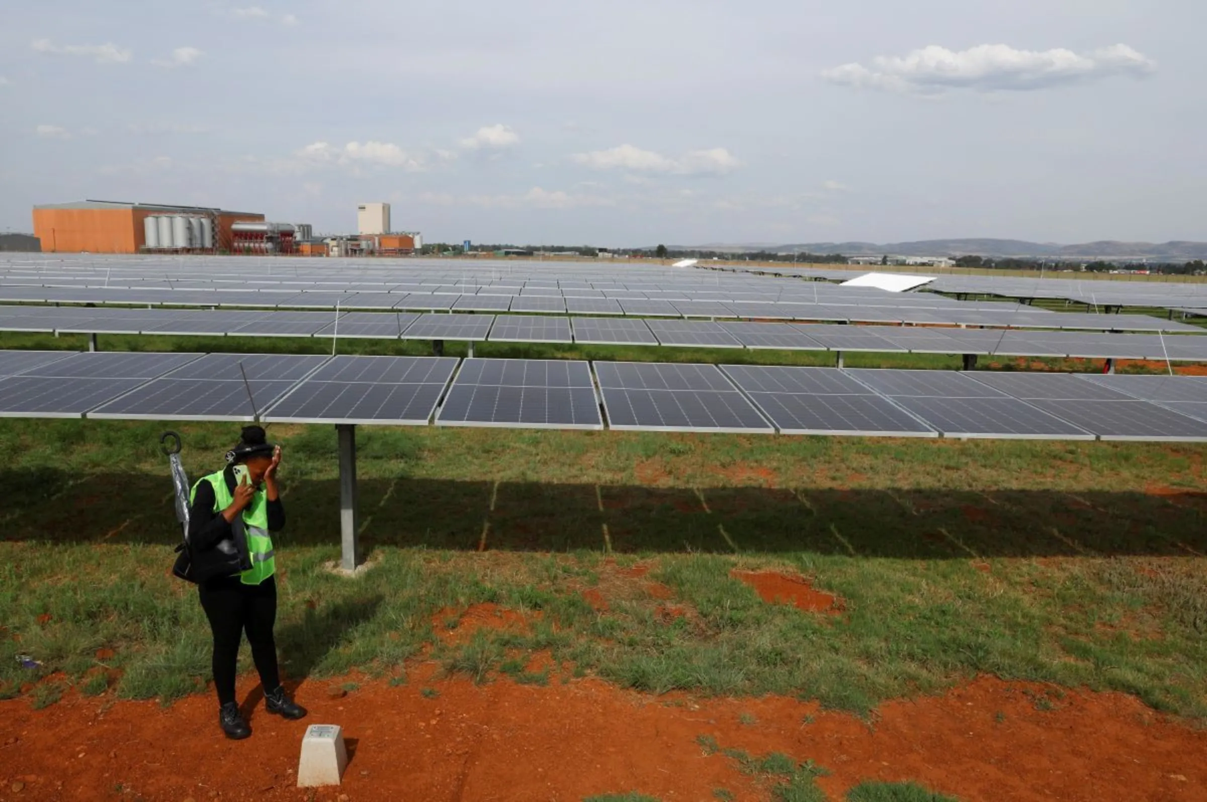 A visitor speaks on the phone while standing next to a new solar power plant in Johannesburg, South Africa, October 26, 2022. REUTERS/Siphiwe Sibeko
