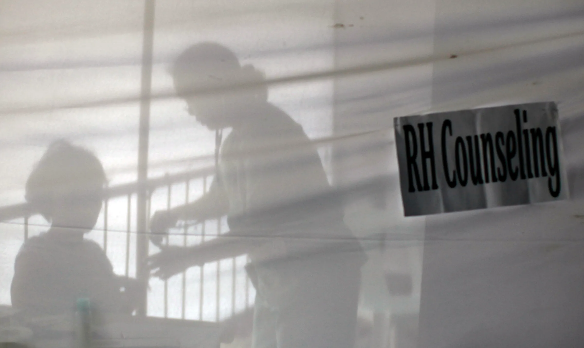 A health worker is silhouetted as she checks up on a woman inside a reproductive health counselling booth during a health fair held to mark World Population Day in Quezon City, Metro Manila July 11, 2009. REUTERS/John Javellana