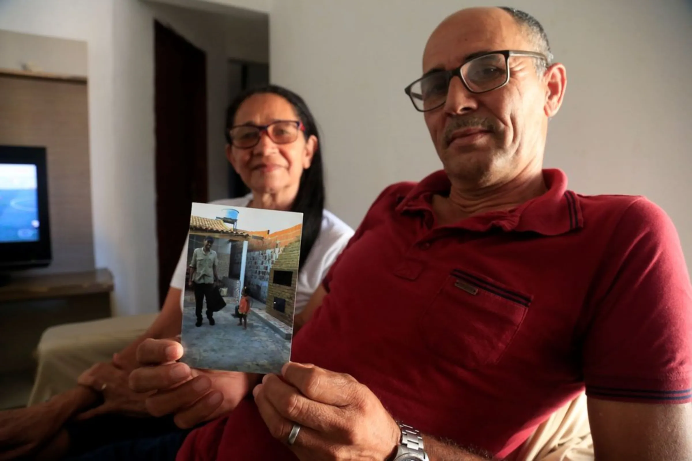 Jose Cicero Lemos, a former sugarcane worker, and his wife, shows off a picture of his younger self in Atalaia, Brazil, September 26, 2021
