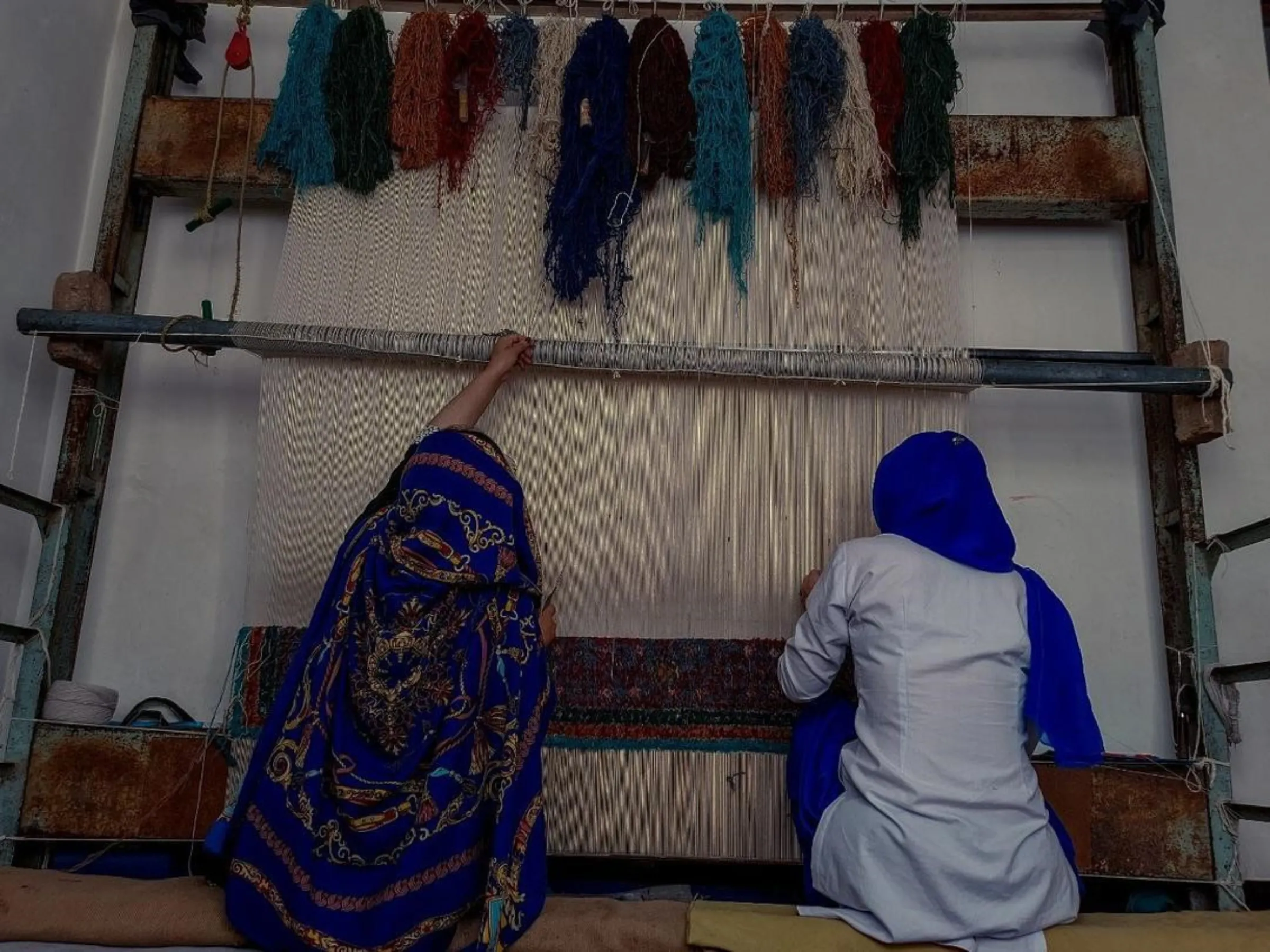 Afghan women weave a rug at a handicraft centre in Kabul run by Laila Haidari. Photo taken August 2023. Handout/Thomson Reuters Foundation