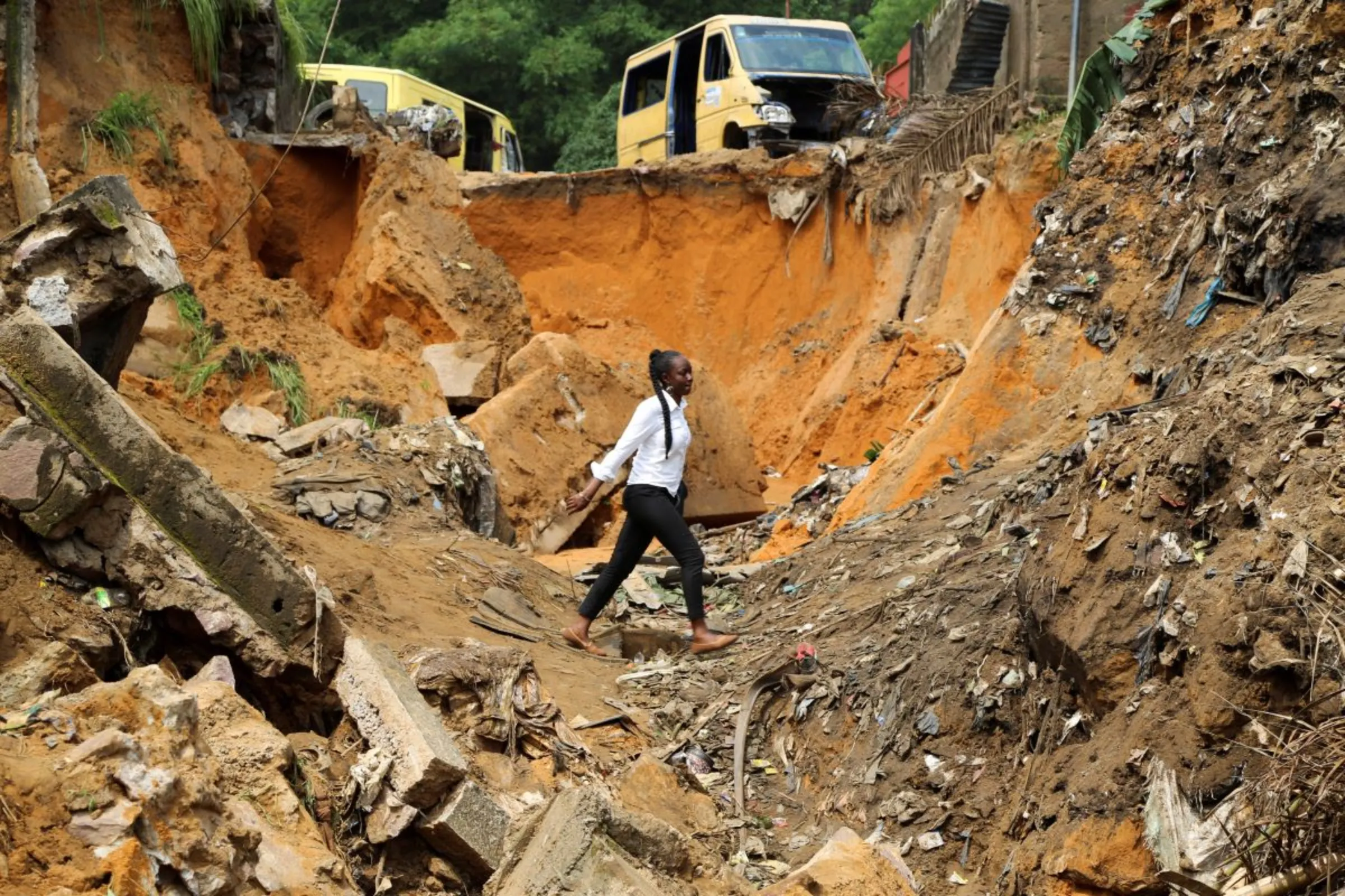 A woman walks through a seriously damaged road after heavy rains caused floods and landslides, on the outskirts of Kinshasa, Democratic Republic of Congo December 14,2022