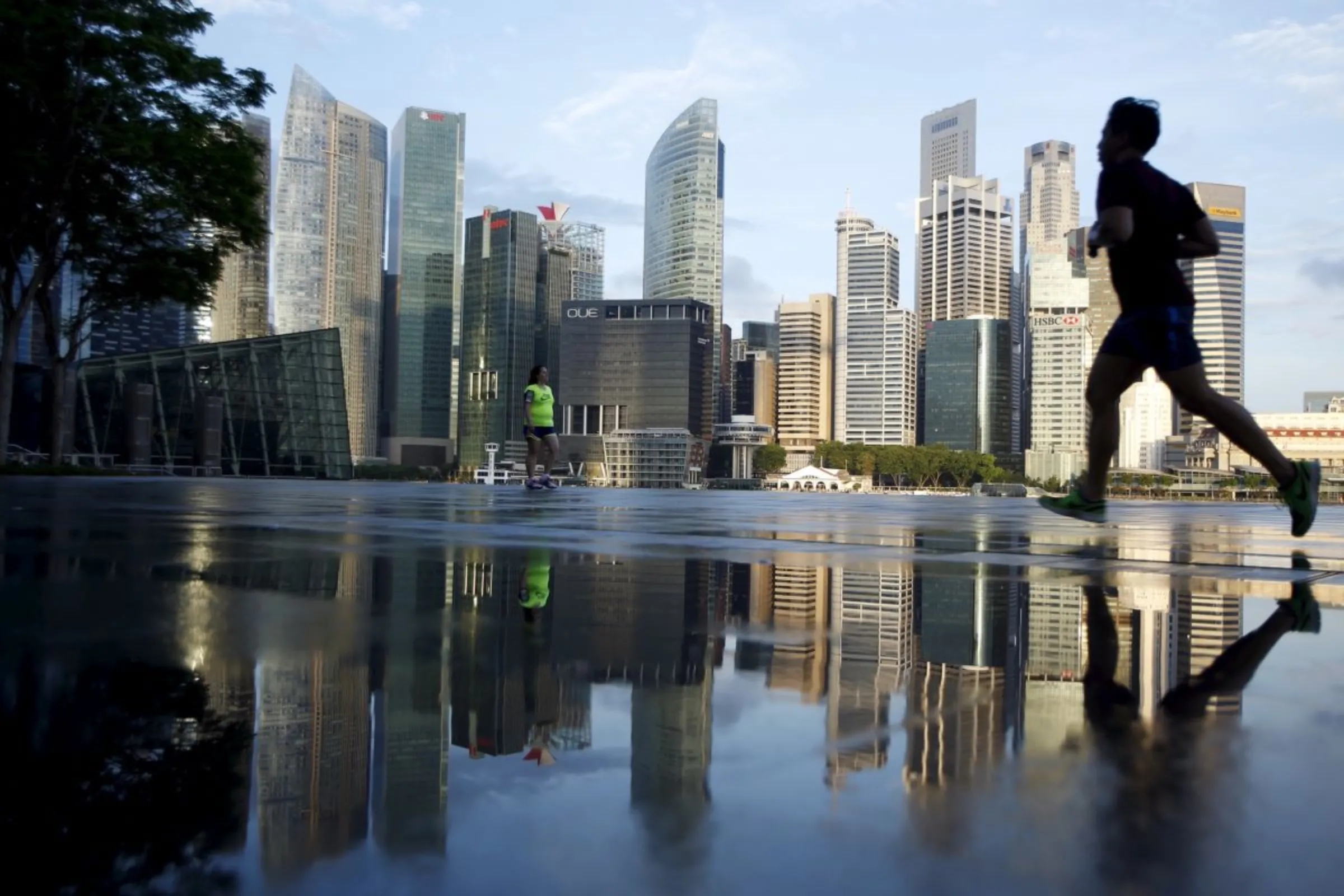 Joggers pass the skyline of the central business district in Singapore April 10, 2015. REUTERS/Edgar Su