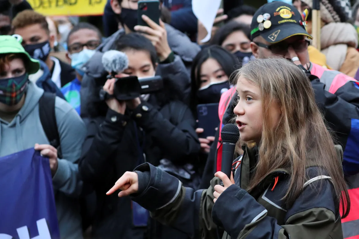 A girl speaks into a microphone surrounded by a crowd with cameramen