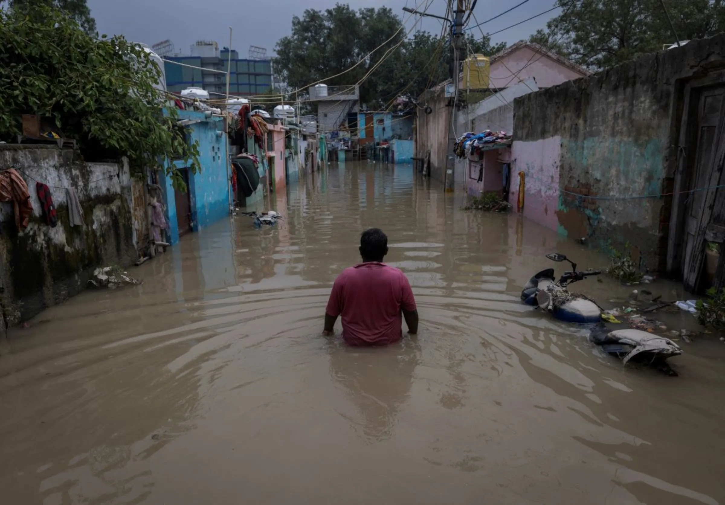 A man walks through a flooded alley at a residential colony, after water rose from the river Yamuna due to heavy monsoon rain, in New Delhi, India, July 14, 2023. REUTERS/Adnan Abidi