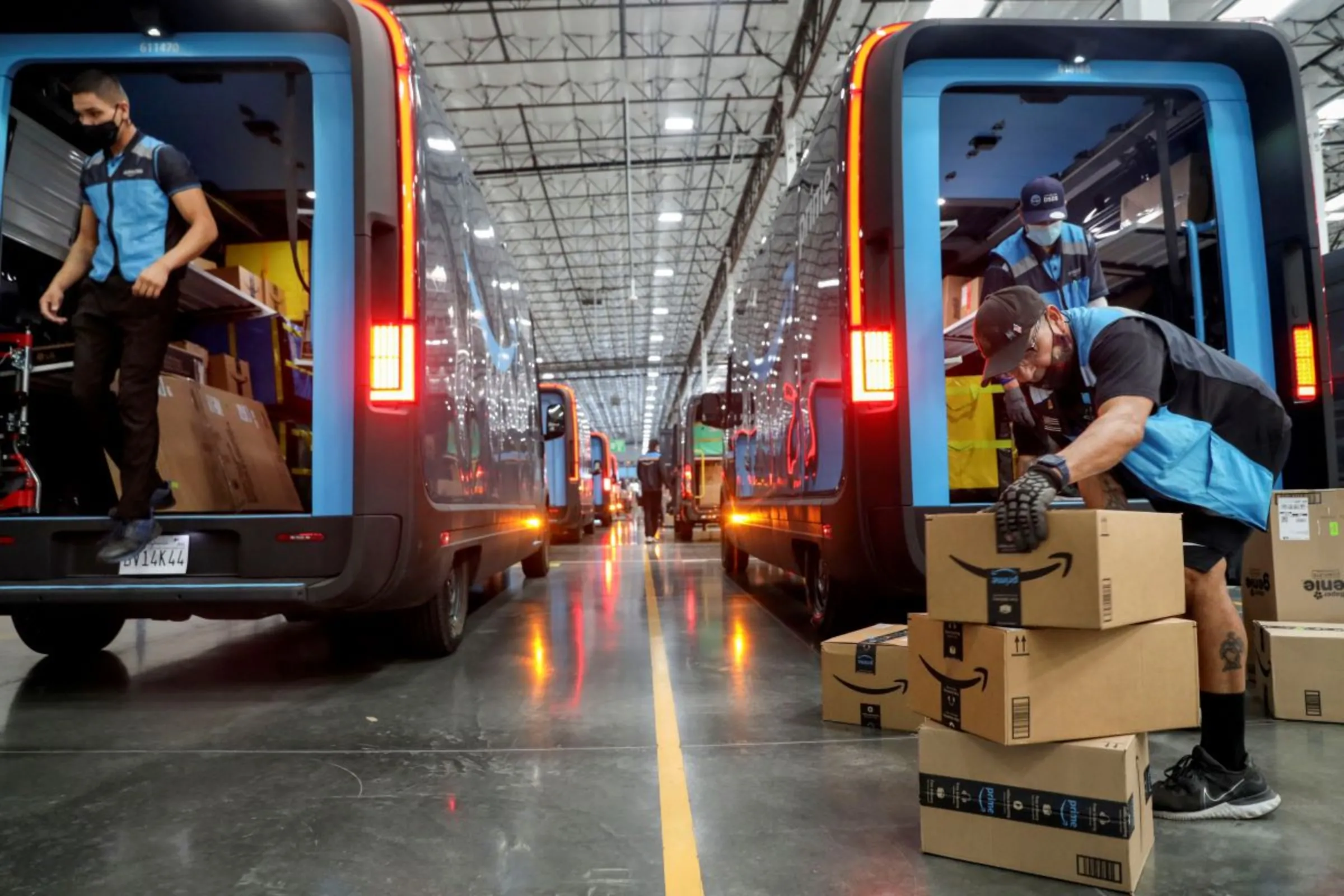 Workers load packages into Amazon Rivian electric trucks at an Amazon facility in Poway, California, U.S., November 16, 2022