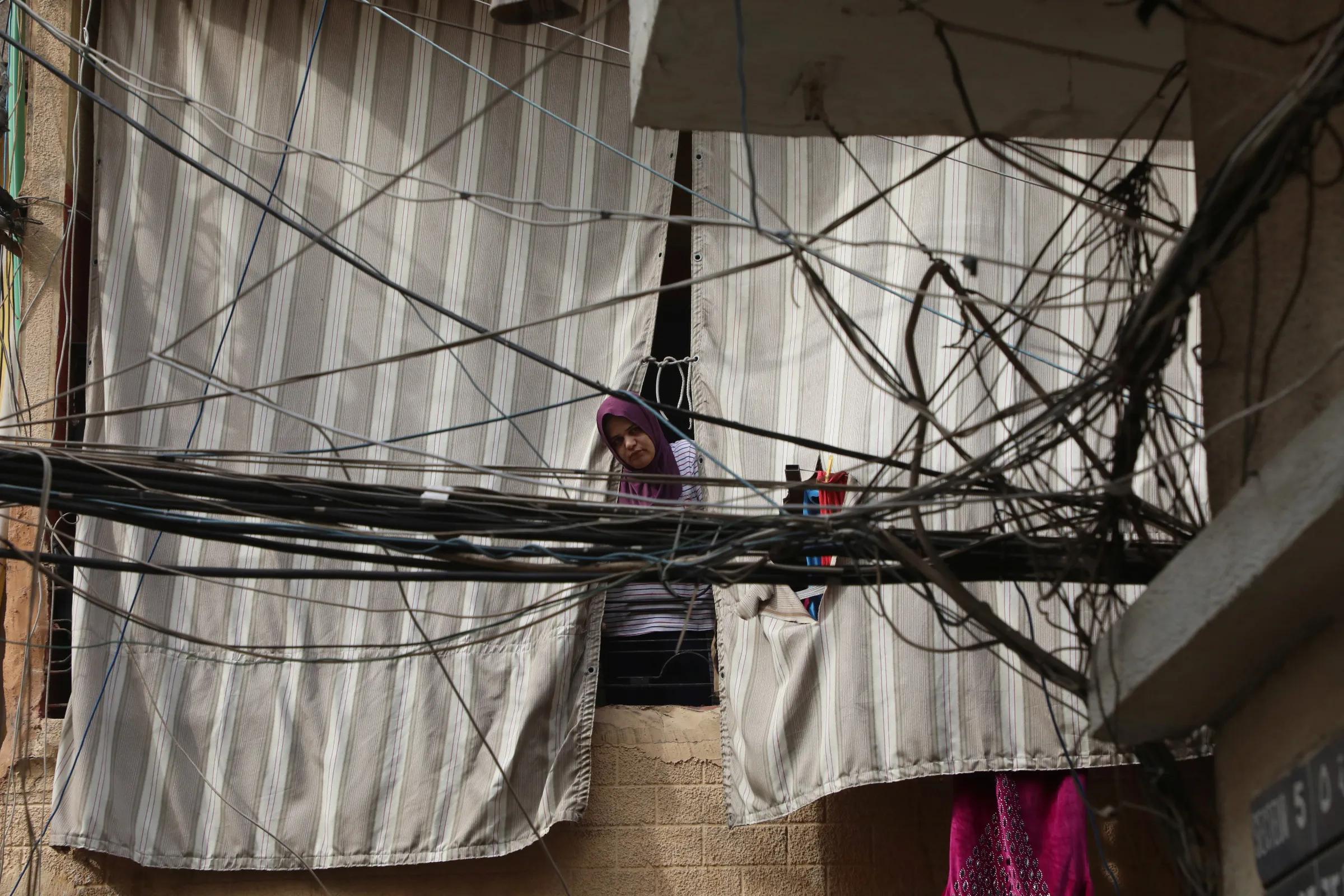 A woman is seen through electricity cables in Bourj Hammoud, Lebanon January 27, 2021. Picture taken January 27, 2021