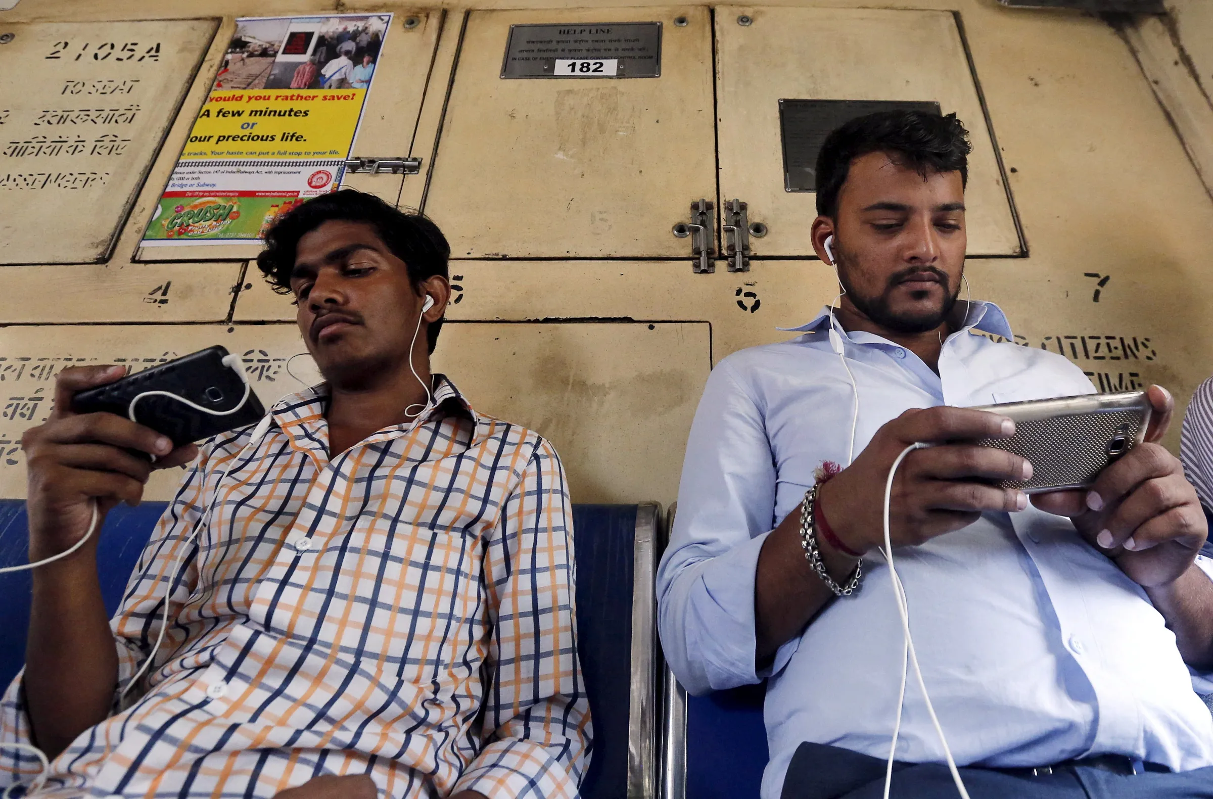 Commuters watch videos on their mobile phones as they travel in a suburban train in Mumbai, India, April 2, 2016. REUTERS/Shailesh Andrade