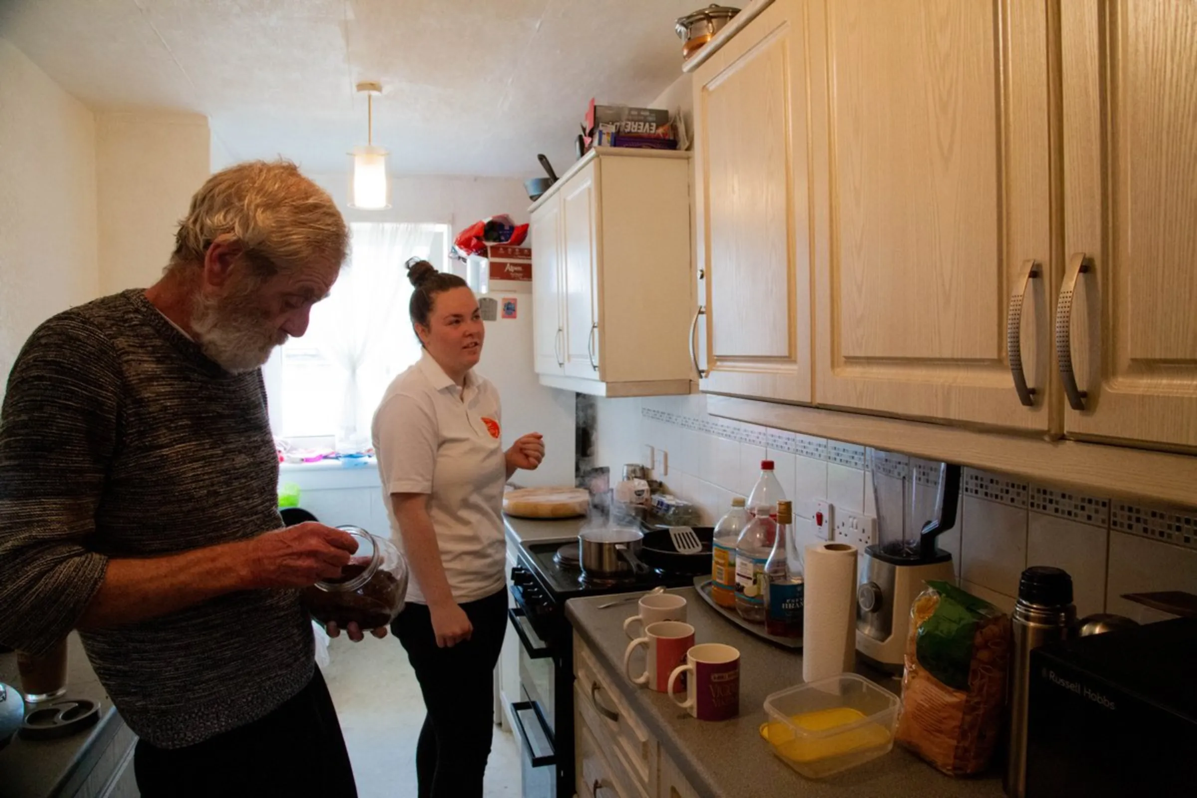 George McGavigan, 62, and his daughter Shelley, 24, make breakfast in their social housing flat in Glasgow, United Kingdom, July 20, 2021. The flat, owned by the Queens Cross Housing Association, has undergone major renovations to improve heat efficiency