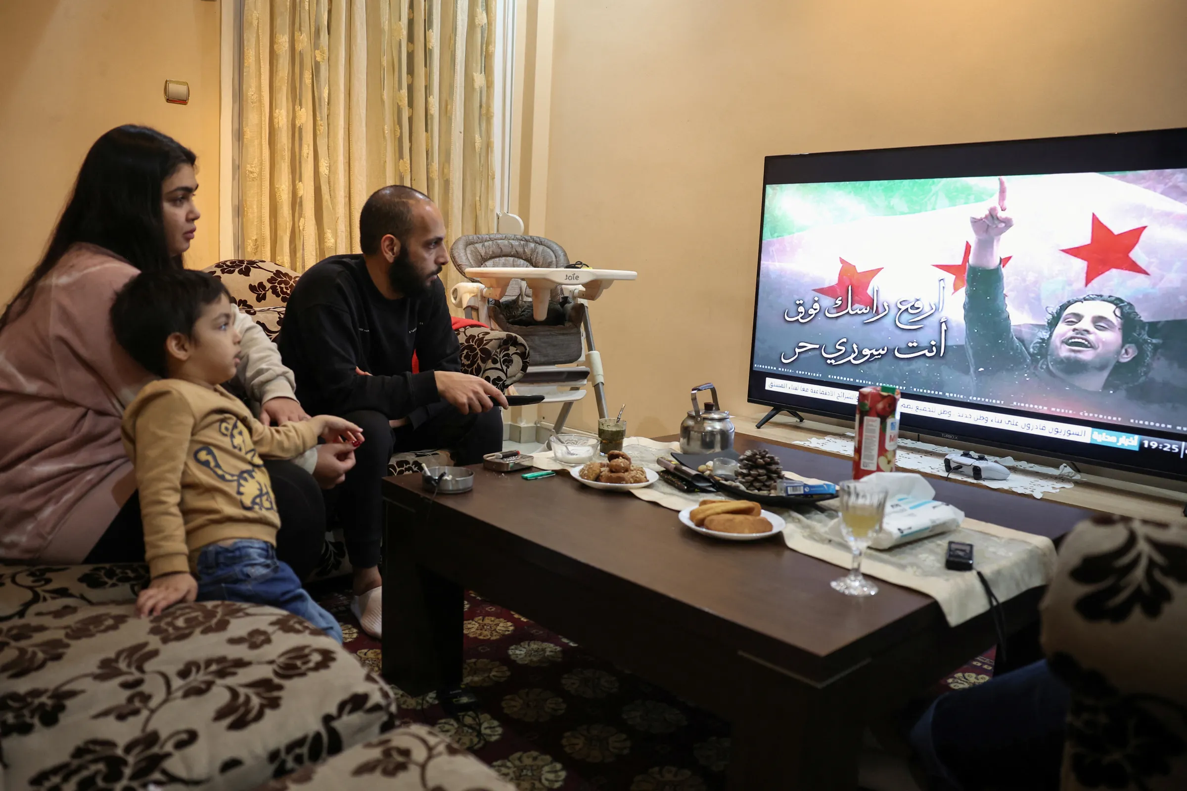 A Syrian family watch news on the events in Syria in their apartment in Athens, Greece, December 10, 2024. REUTERS/Louisa Gouliamaki