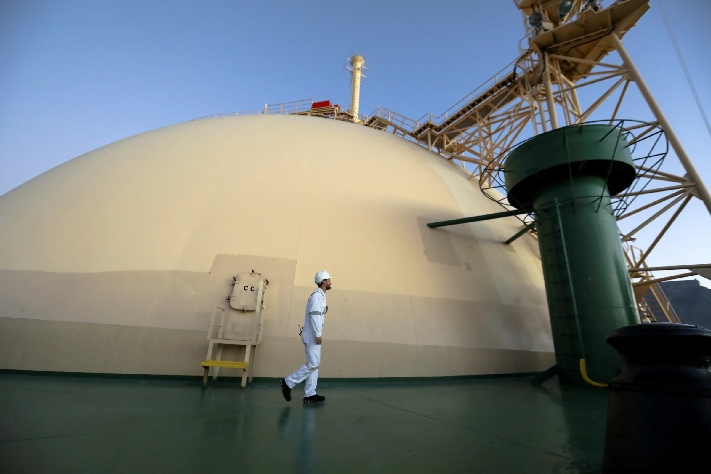 A worker walks past a dome holding liquefied natural gas, on the vessel KARMOL LNGT Powership Asia, one of 37 floating storage and regasification units (FSRU) in the world, as it docks at the Cape Town port en route to Brazil, in Cape Town, South Africa, April 19, 2022