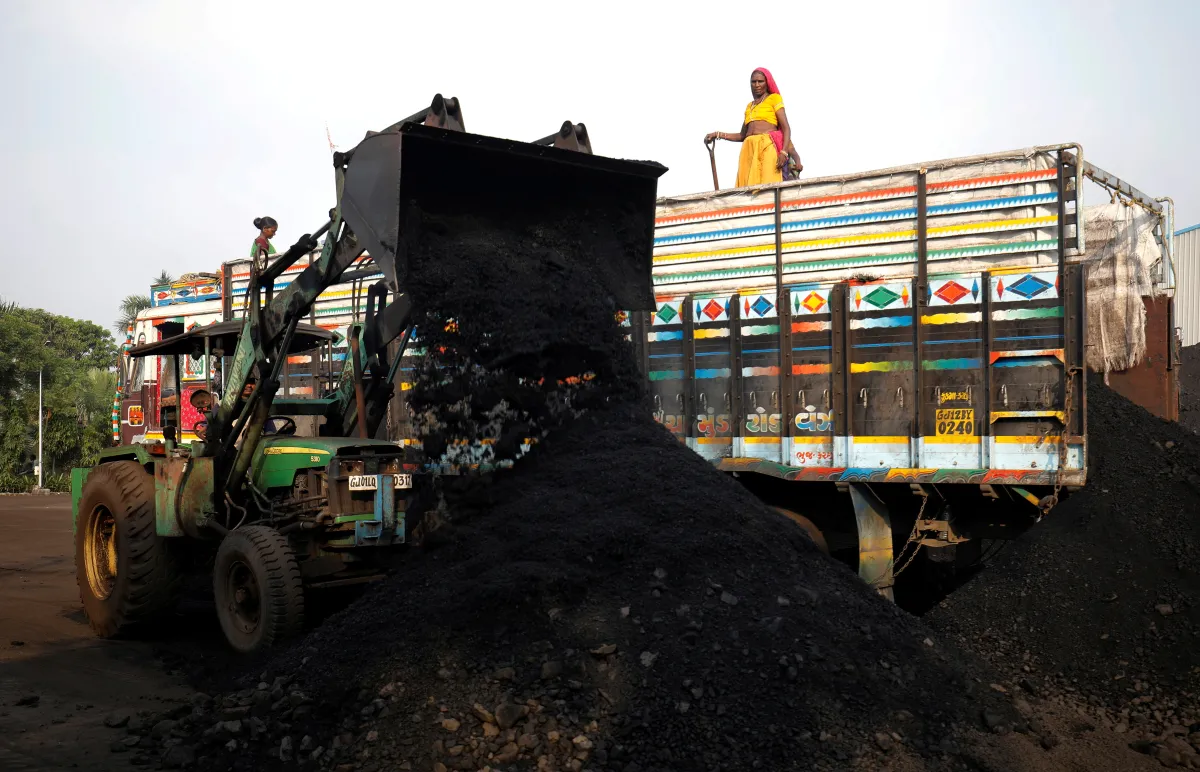 A woman stands on top of a supply truck as workers unload coal from a supply truck at a yard on the outskirts of Ahmedabad, India October 12, 2021. REUTERS/Amit Dave