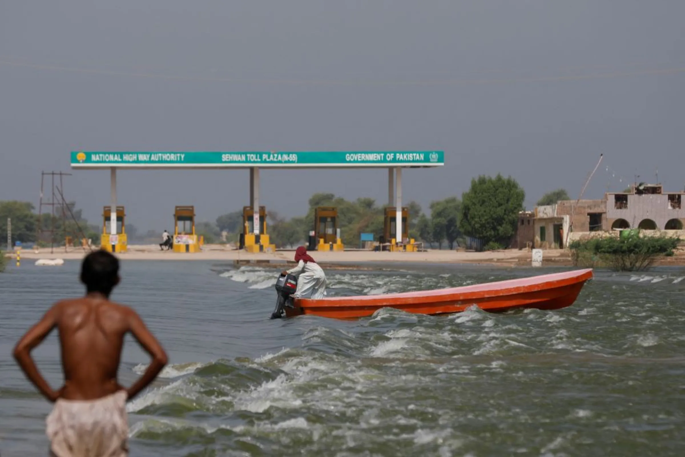 A man rides a boat past toll plaza amid flood water on main Indus highway, following rains and floods during the monsoon season in Sehwan, Pakistan September 15, 2022