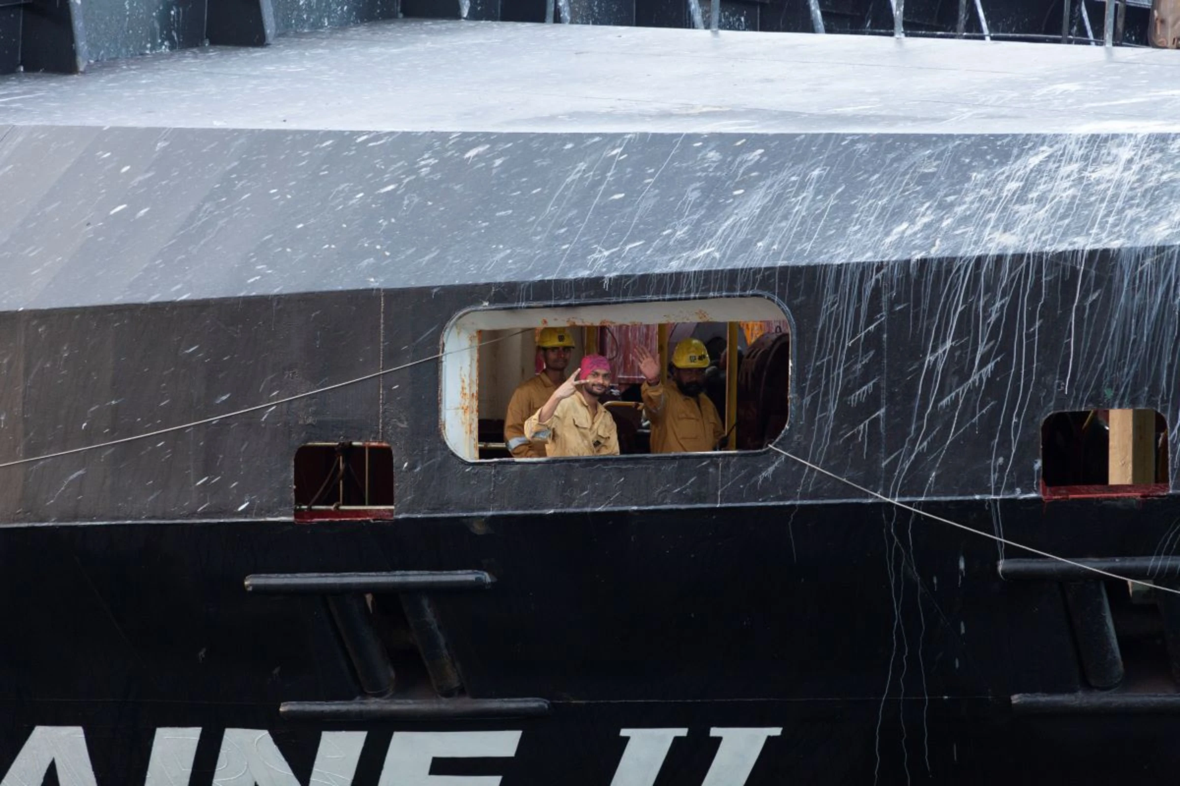 Members of a container ship’s crew wave as their vessel crosses through the Miraflores locks of the Panama Canal, February 15, 2024. Thomson Reuters Foundation/Enea Lebrun