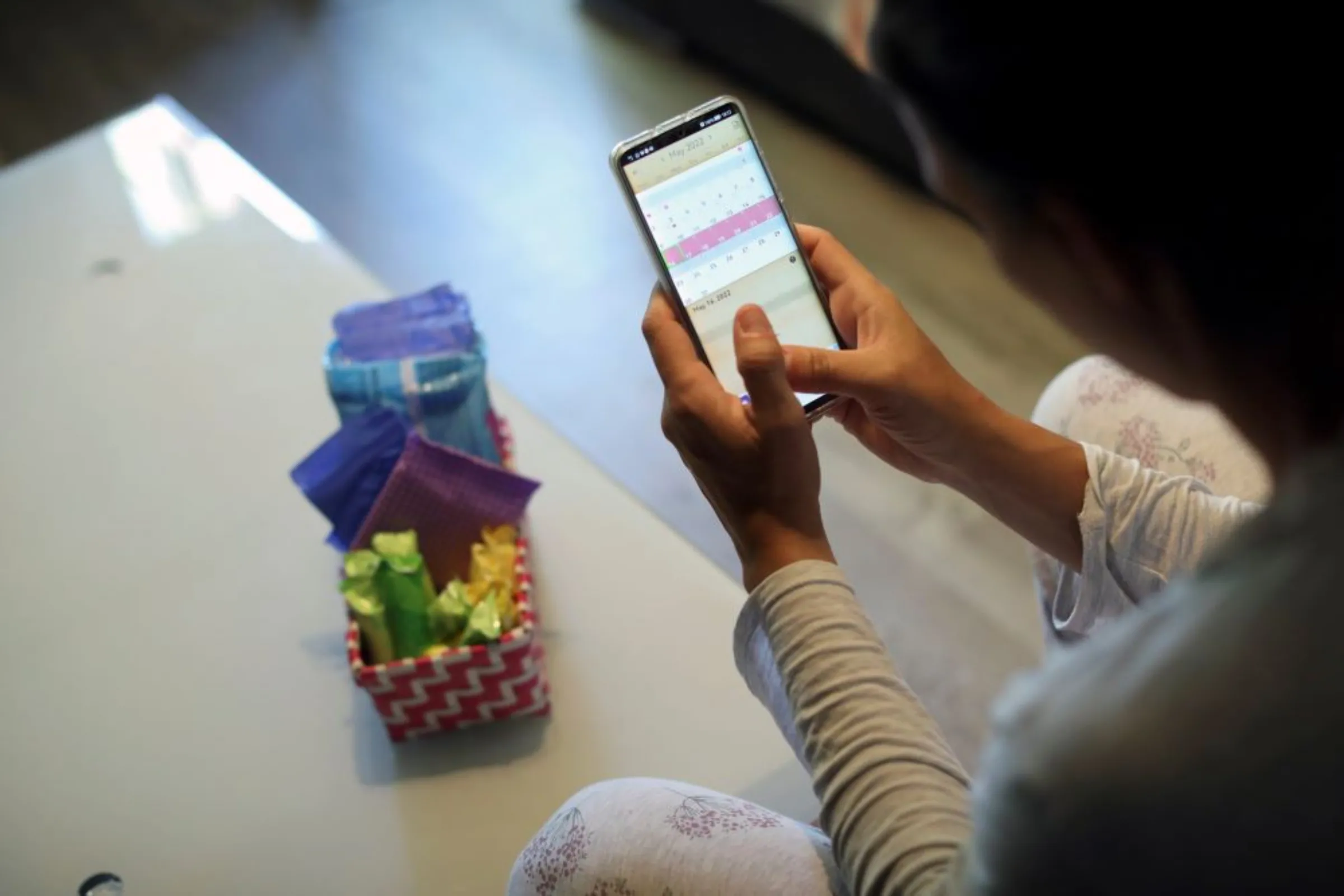 A woman poses as she observes a period calendar tracker app on her mobile phone at her home in Madrid, Spain, May 16, 2022