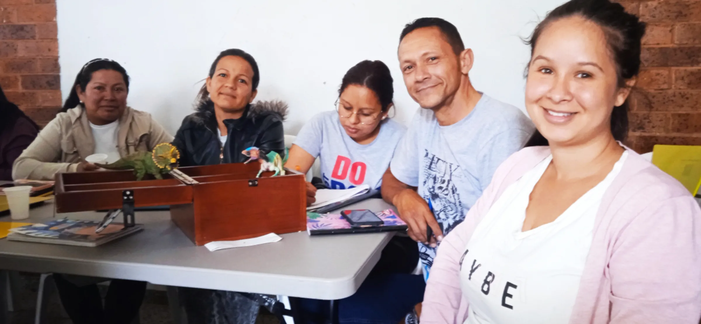 Venezuelan migrant Jhanndre Arteaga sits next to a community savings box at a financial literacy and entrepreneurship workshop in Bogota, Colombia. June 14, 2023