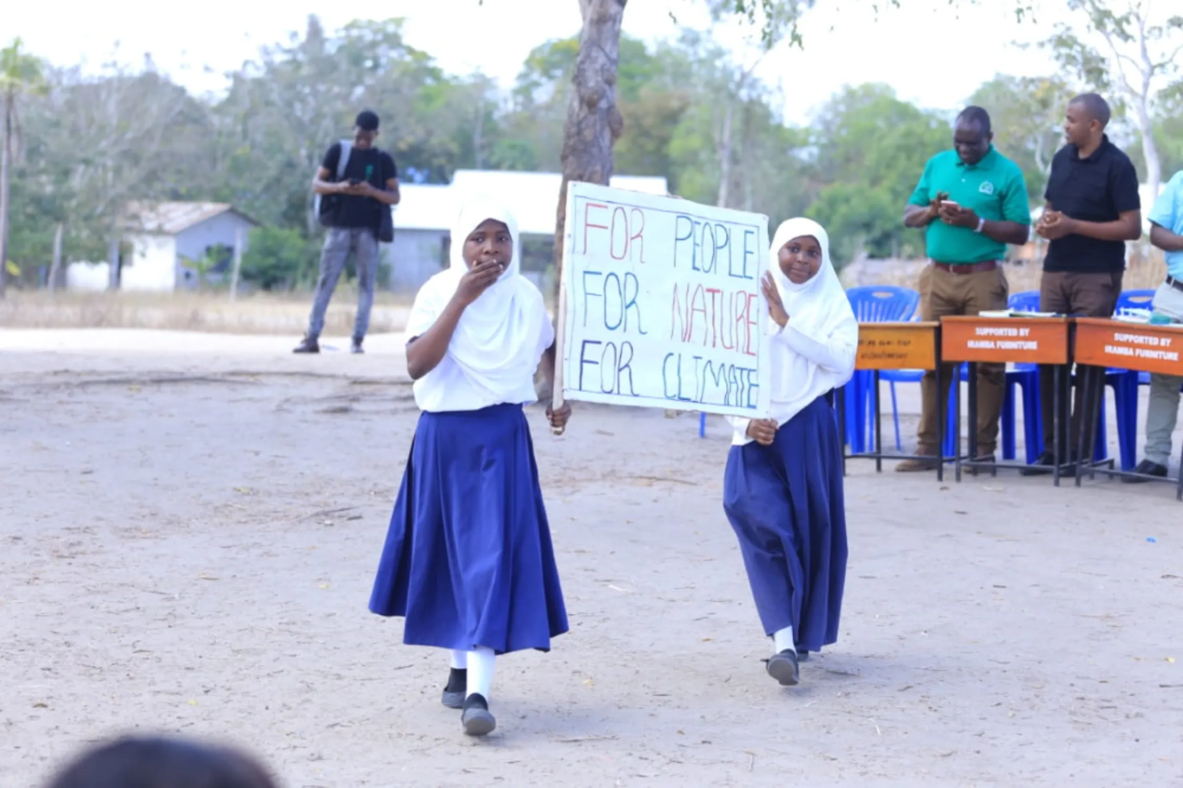 Two young students hold a sign reading ‘For People, For Nature, For Climate’ at a climate strike in the Kibaha district, Tanzania, October 9, 2022