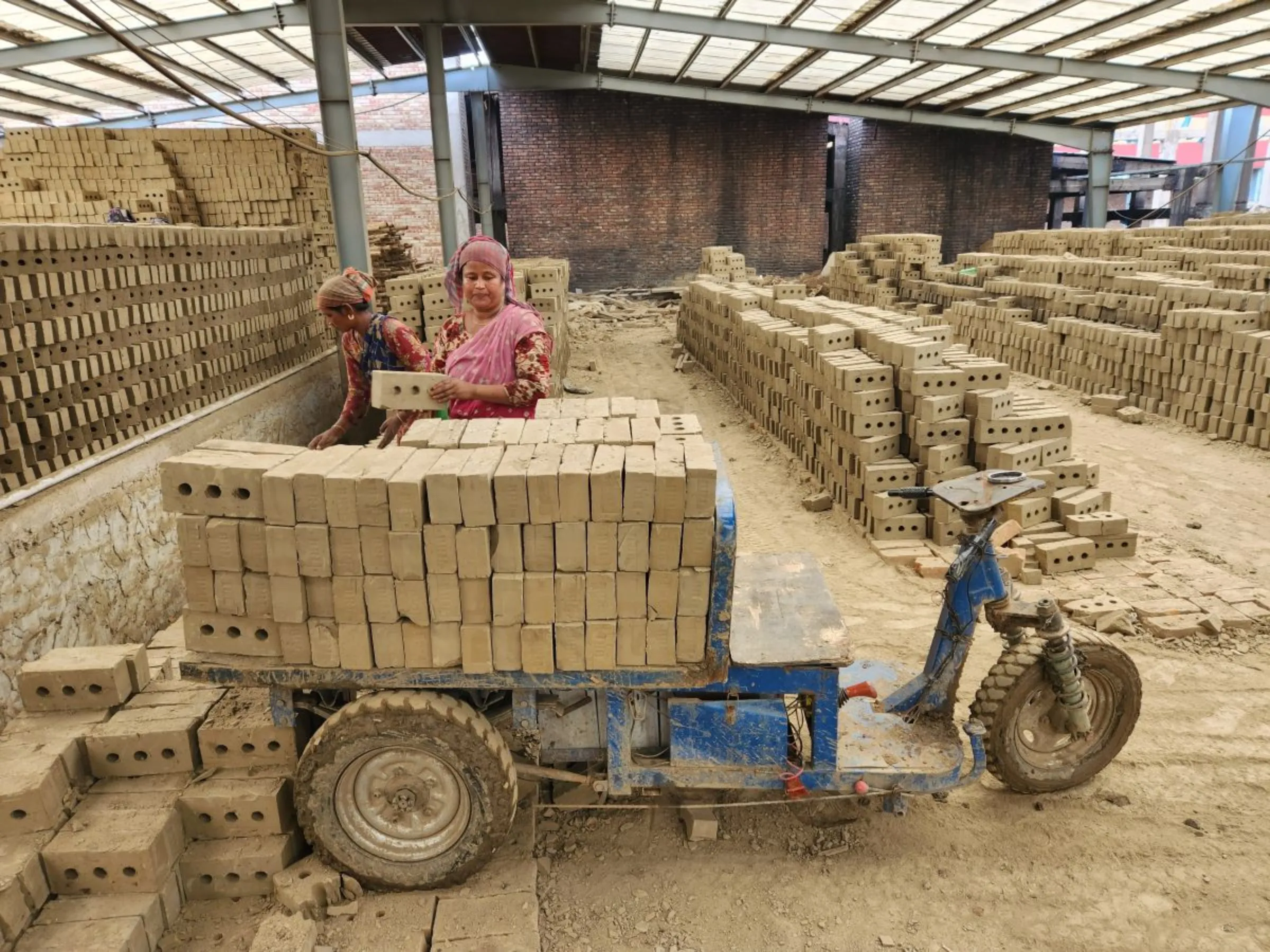 Two female workers are loading machine made raw bricks in a vehicle for burning at Banolata Bricks Refractory Ltd. Natore, Northern Bangladesh June 30, 2023