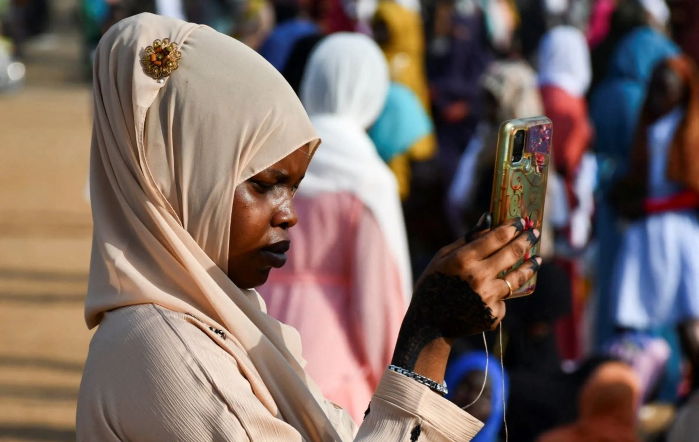 A Muslim woman uses her mobile phone before attending prayers on the first day of Muslim holiday of Eid al-Adha, at the Zahara Square in Juba, South Sudan, June 28, 2023