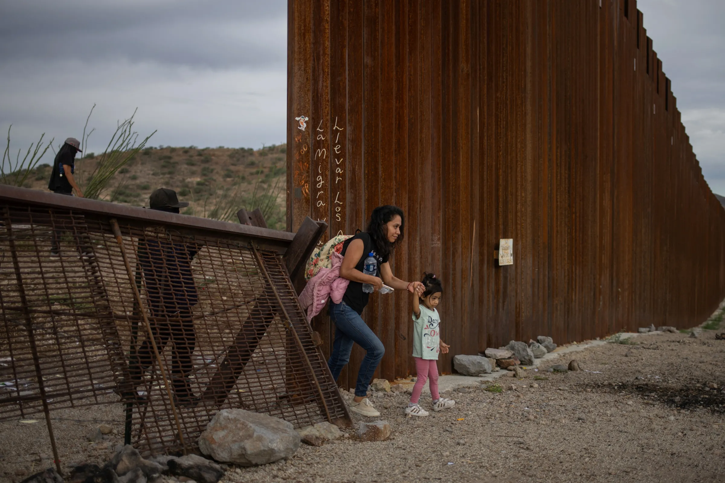 Smugglers are seen to the left in Sonora, Mexico as they transport a mother and her daughter from El Salvador past the Border Wall into the United States in Ruby, Arizona, U.S., June 26, 2024. REUTERS/Adrees Latif