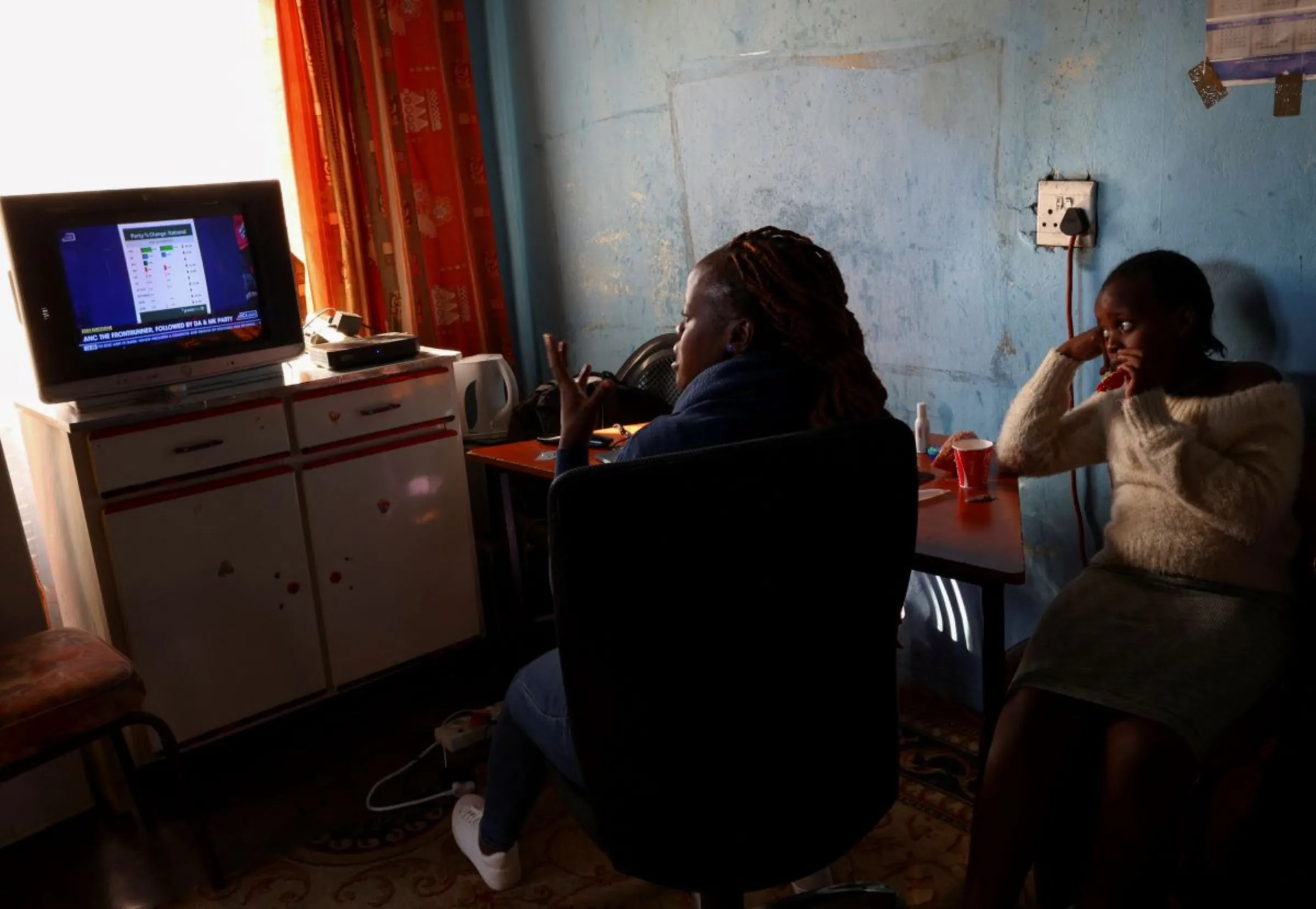 Women watch the election results on TV in Soweto's township, South Africa, June 1, 2024. REUTERS/Siphiwe Sibeko