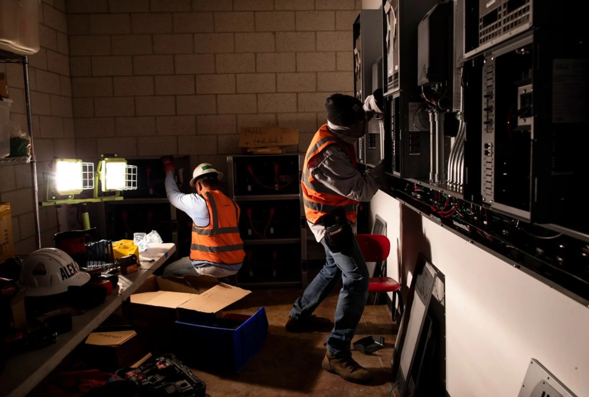 Darean Nguyen and Alejandro DeLeon work on an electrical installation to process energy produced by solar panels on the rooftop of the Audubon Center in Los Angeles, California, May 21, 2021