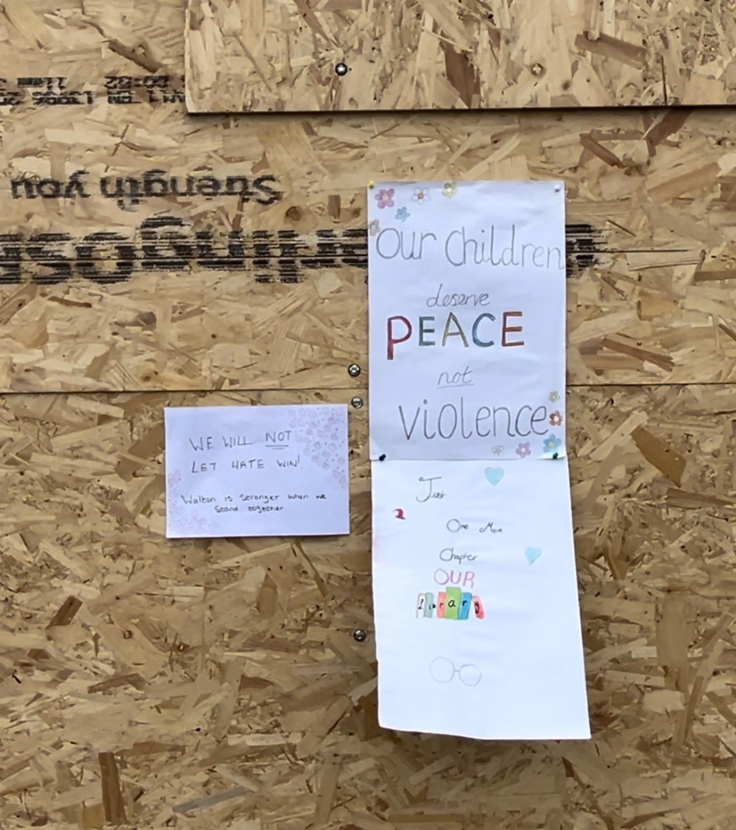 Signs reading 'our children deserve peace not violence' are pinned to the boarded up Spellow Lane Library Hub in Walton, Liverpool, after it was set alight during riots in the city. August 5, 2024. Thomson Reuters Foundation/Lucy Middleton