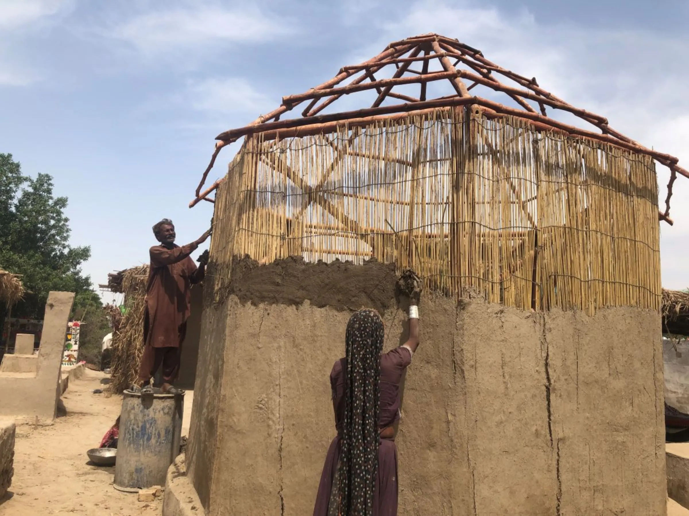 Workers hired by the Heritage Foundation of Pakistan plaster an eight-sided safe room being in the flood-ravaged Wasram village, Tando Allah Yar District, Pakistan, April 9, 2023. Thomson Reuters Foundation/Zofeen T. Ebrahim