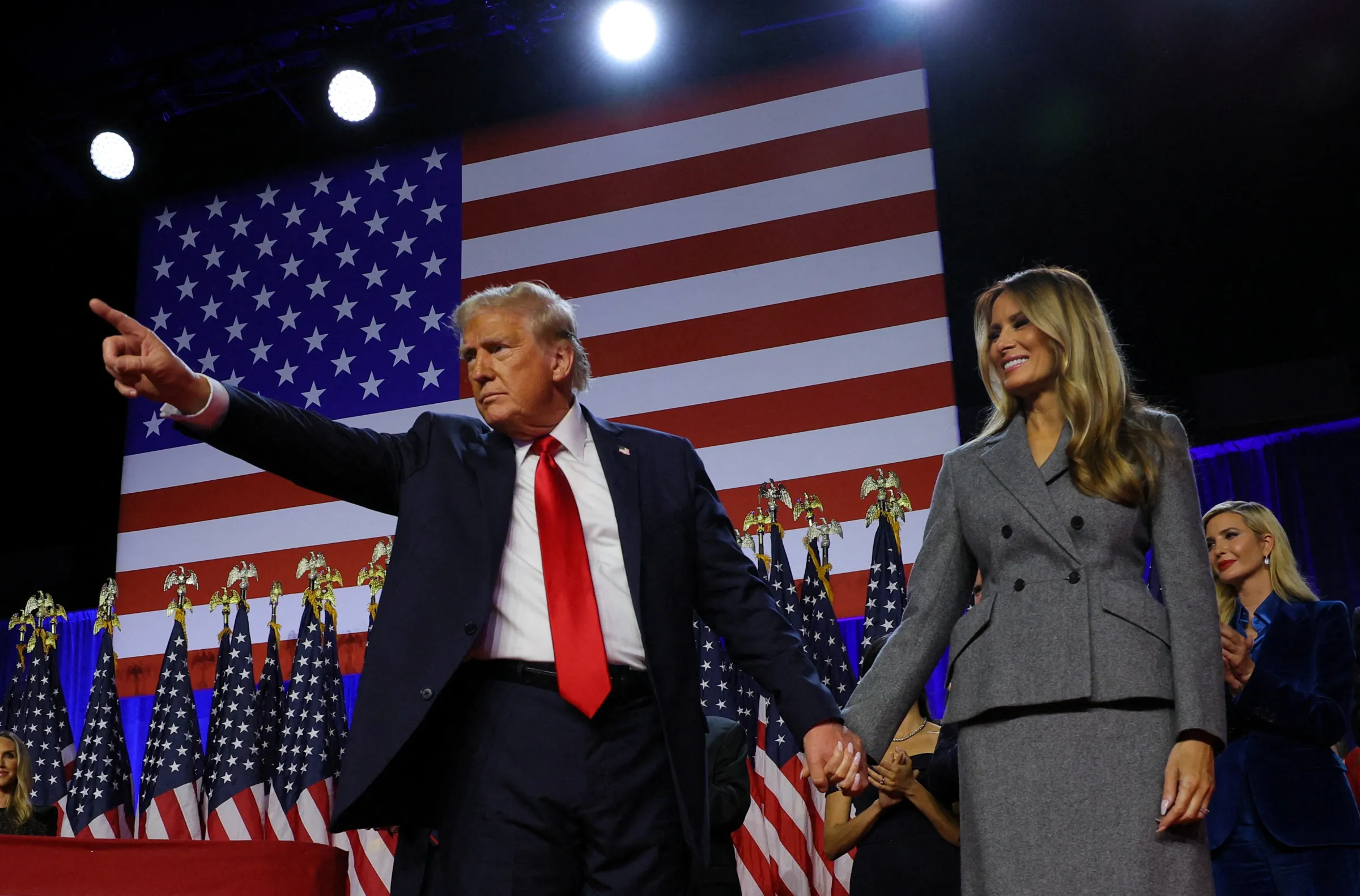 Republican presidential nominee and former U.S. President Donald Trump gestures as he holds hands with his wife Melania during his rally, at the Palm Beach County Convention Center in West Palm Beach, Florida, U.S., November 6, 2024. REUTERS/Brian Snyder