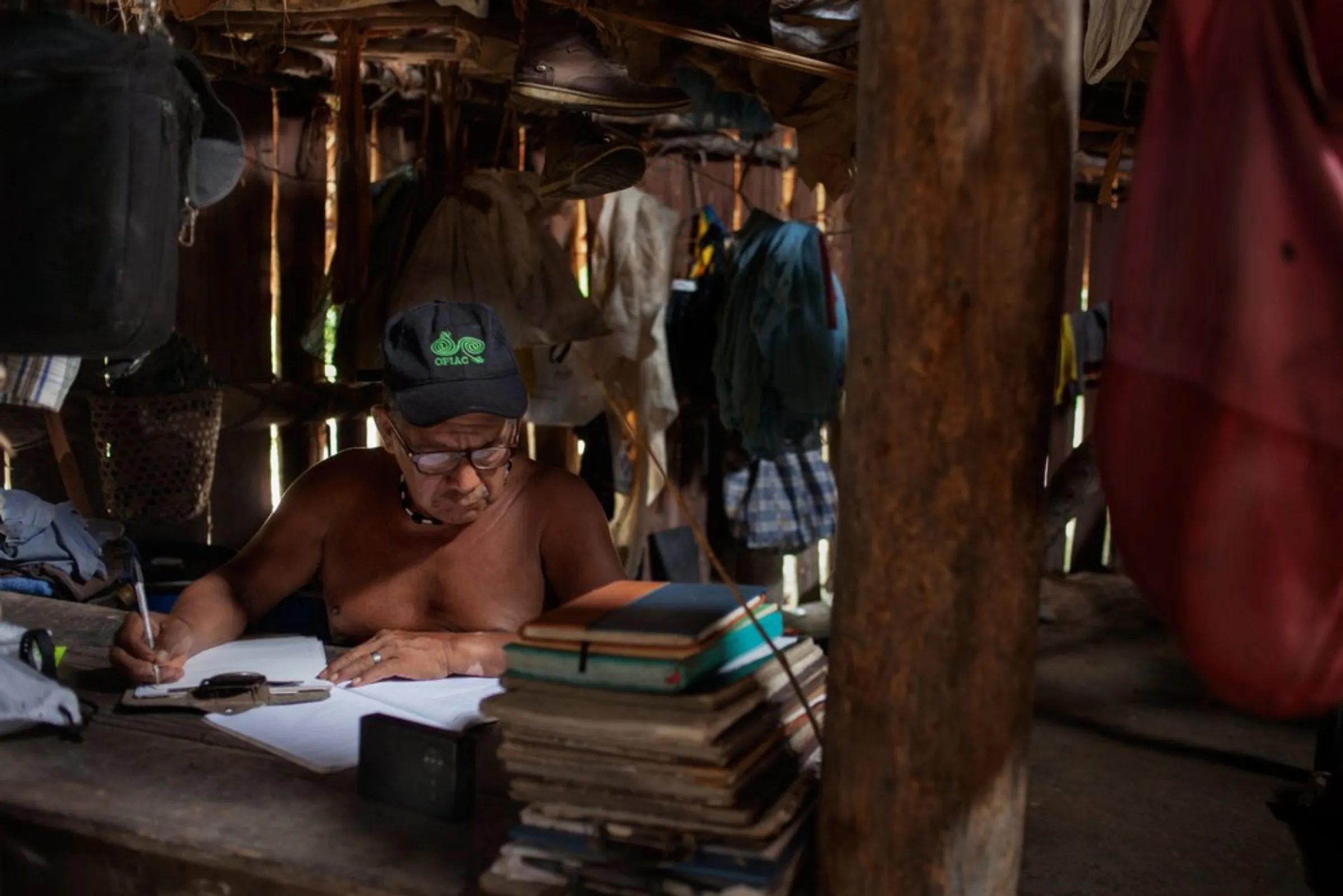 Shaman Faustino Matapi, the spiritual leader of the Puerto Libre community of 13 families who live along the Miriti-Parana River in Colombia’s southeast Amazonas province, does paperwork in a traditional dwelling called a maloka, December 19, 2021