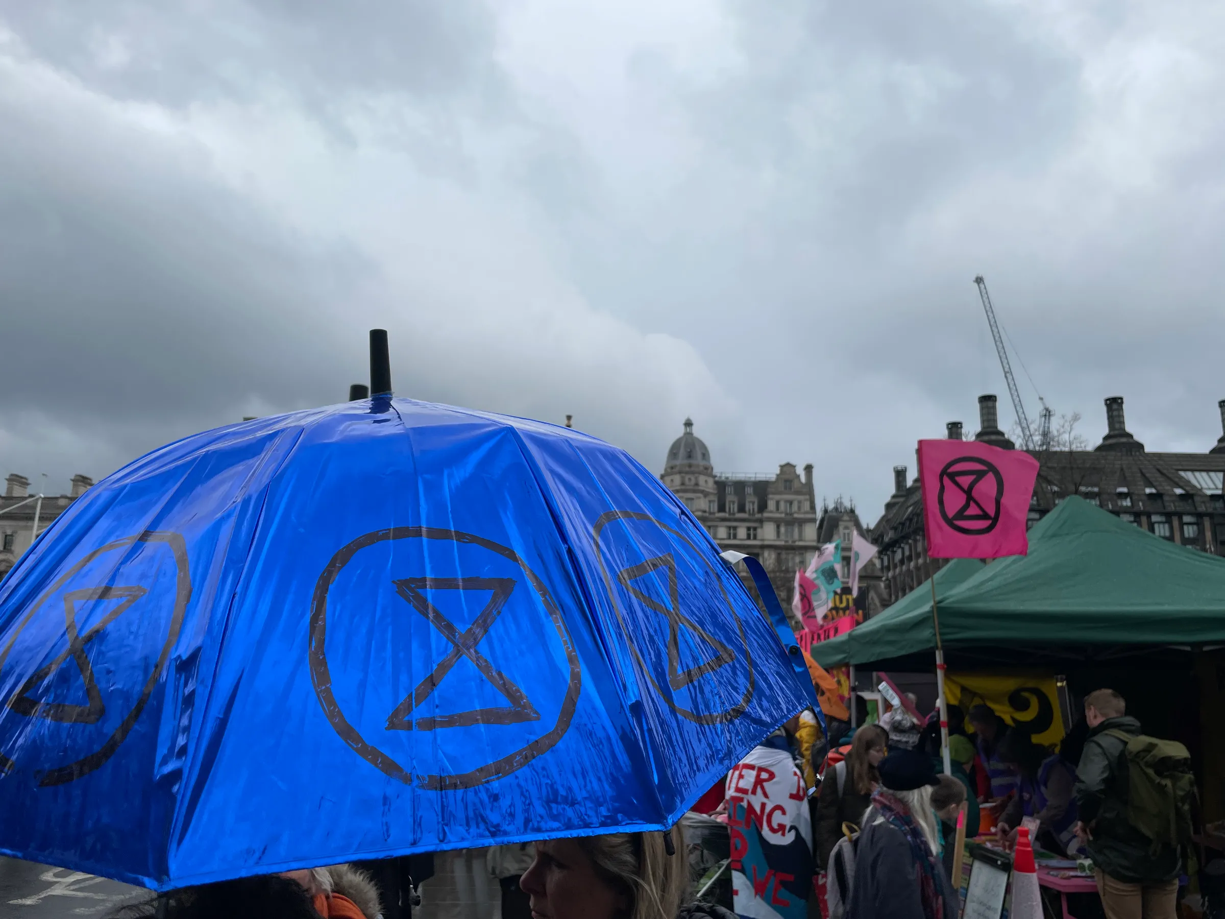 A blue umbrella marked with the Extinction Rebellion symbol was among those carried during a rainy protest organised by Extinction Rebellion outside Parliament in London on April 21, 2023. Thomson Reuters Foundation/Laurie Goering
