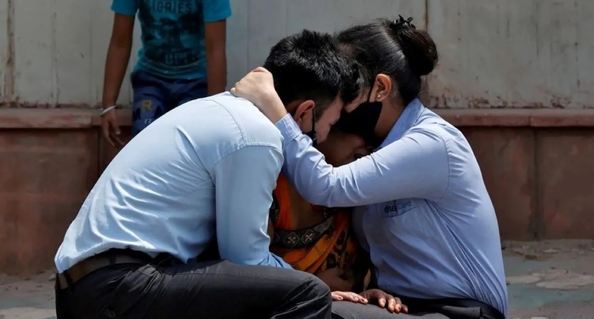 A woman is consoled by her children after her husband died from complications related to the coronavirus disease (COVID-19) outside a mortuary of a COVID-19 hospital in New Delhi, India, April 15, 2021. REUTERS/Danish Siddiqui