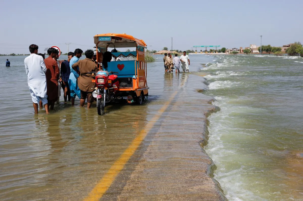 Displaced people stand on flooded highway, following rains and floods during the monsoon season in Sehwan, Pakistan, September 16, 2022.