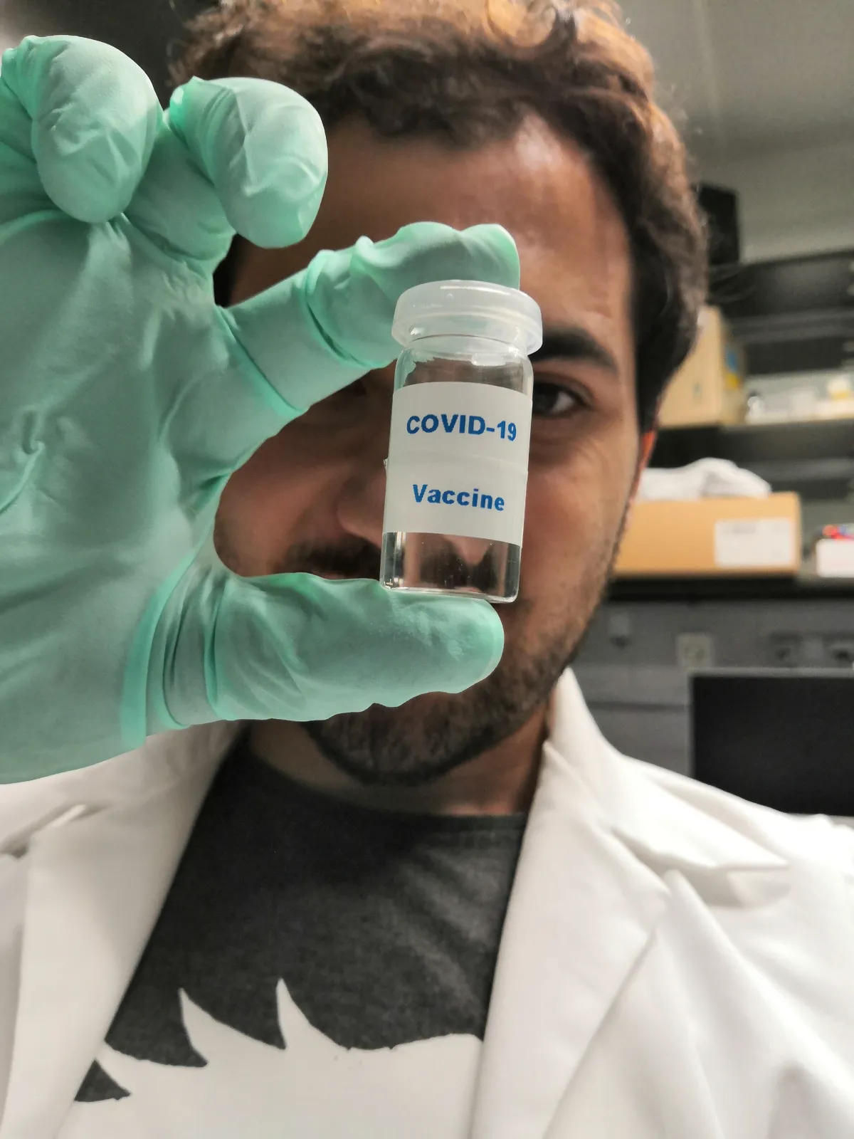 A man with gloved hands holds up a COVID-19 vaccine