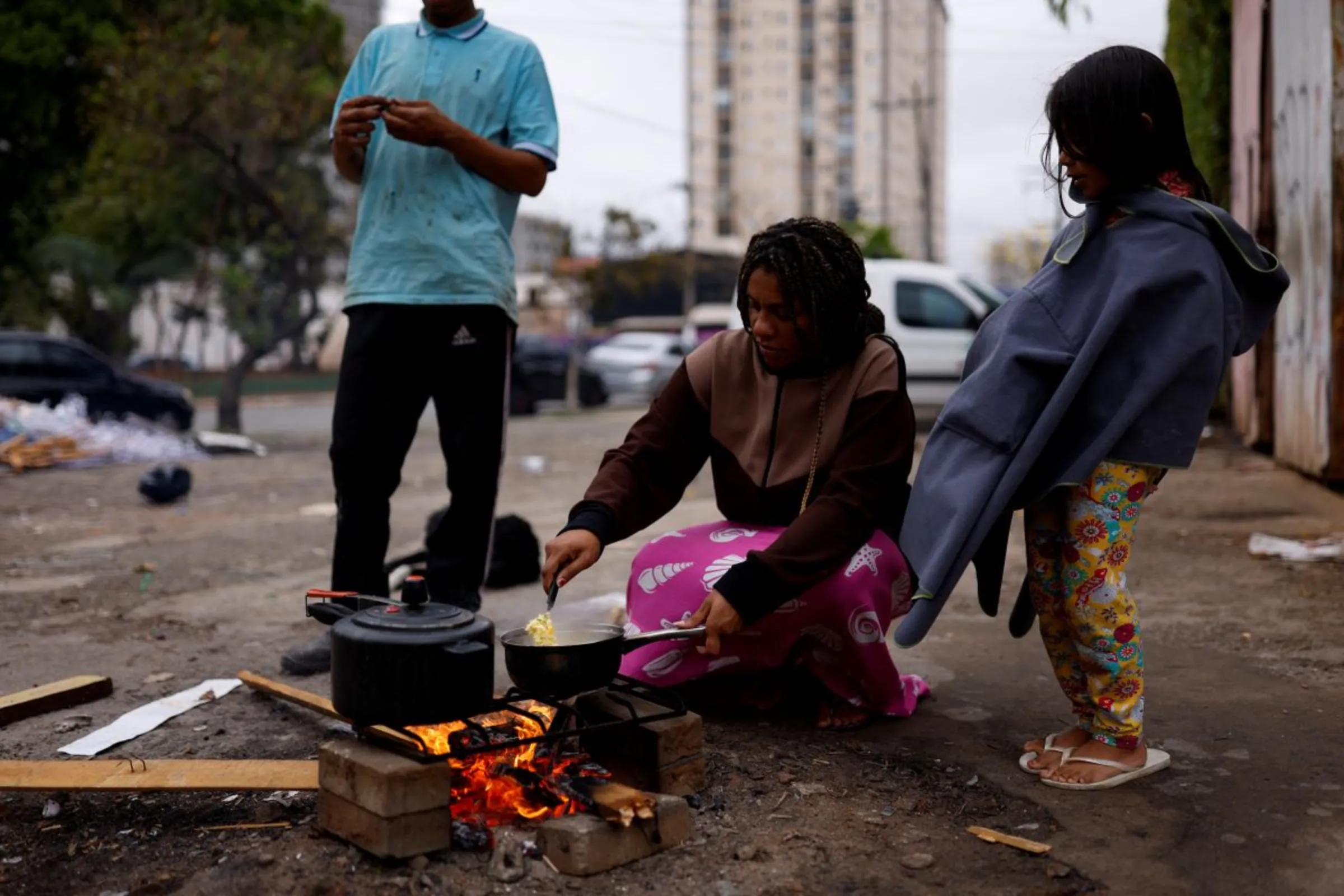 A pregnant woman burns wood on the street to cook a meal for her husband and their daughter outside their home in Sao Paulo, Brazil, September 16, 2022