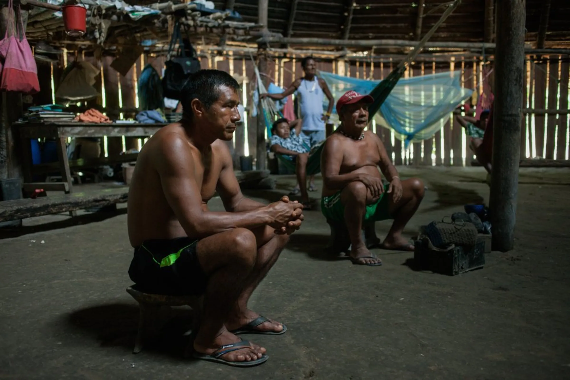 Lucio Matapi, 'captain' of the Puerto Libre community, sits next to his father, shaman Faustino Matapi, during a meeting in Miriti-Parana, a rainforest village in Colombia’s southeast Amazonas province, December 16, 2021