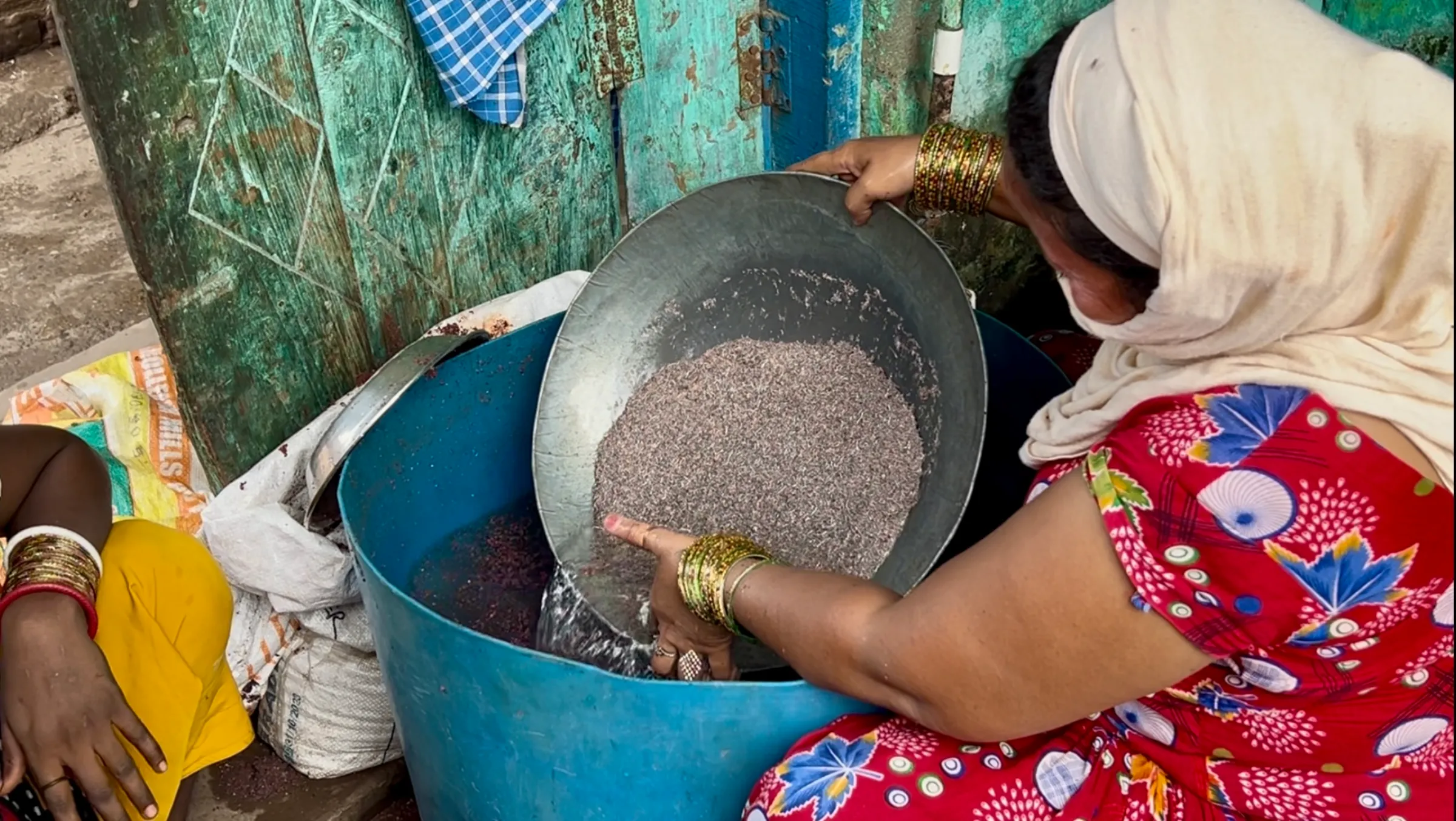 Women using water and a sieve to filter out metals from the dust of freshly cut wires in Seelampur, Delhi. July 12, 2025. Thomson Reuters Foundation/Bhasker Tripathi
