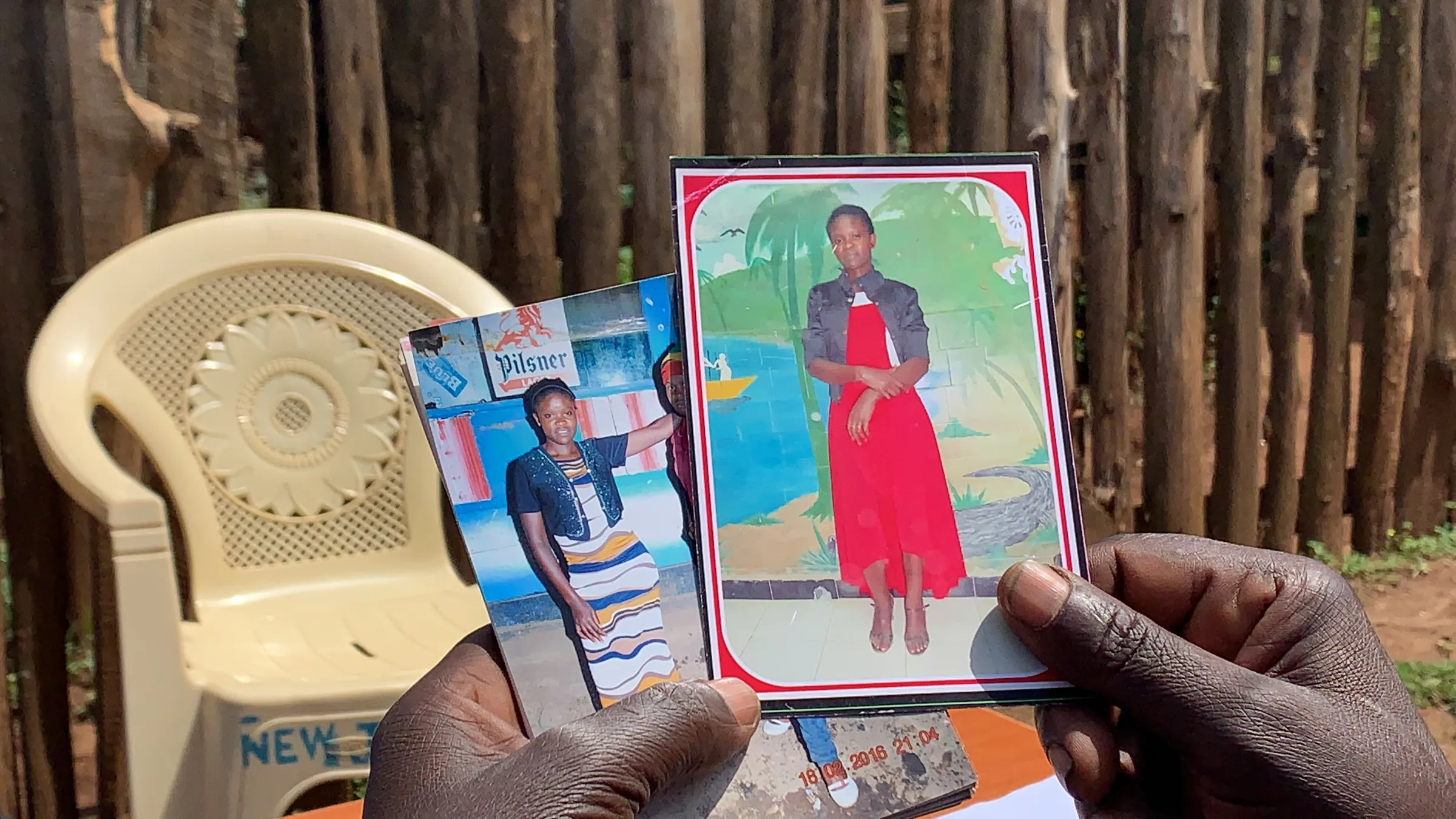 John Tindo looks at pictures of his daughter Alice Awor Tindo who died while working in Saudi Arabia