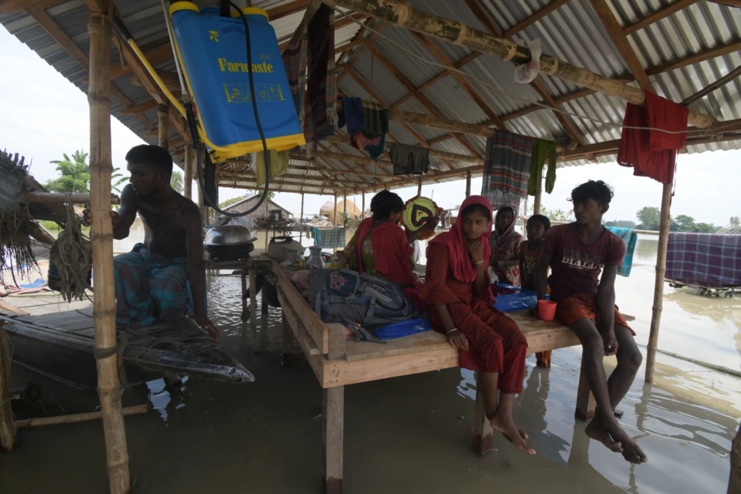 Amid surging floods, a family waits for a boat to move to safety along with their belongings in Bogura, northern Bangladesh, September 17, 2023