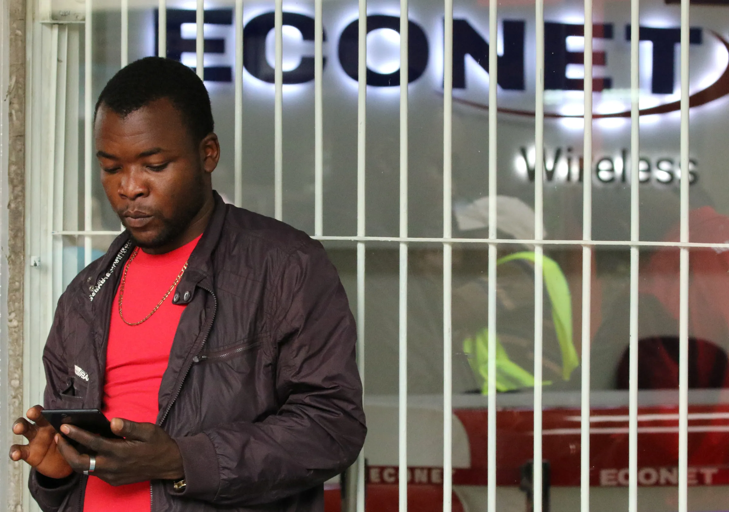 A man uses his mobile phone in front of a telecoms store in Harare, Zimbabwe, January 13, 2017