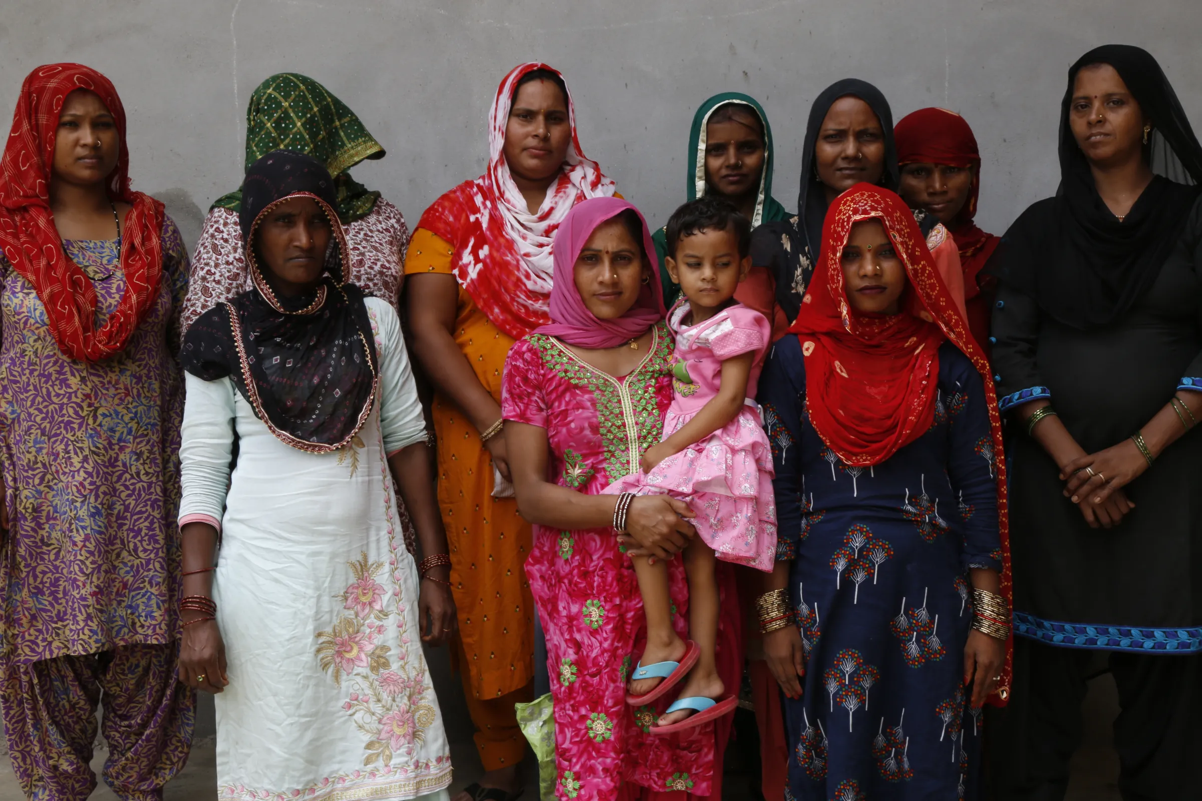 A woman holds a child in a group of trafficked brides posing for a photo in a village in Hisar, India, July 31, 2022. Thomson Reuters Foundation/Annie Banerji
