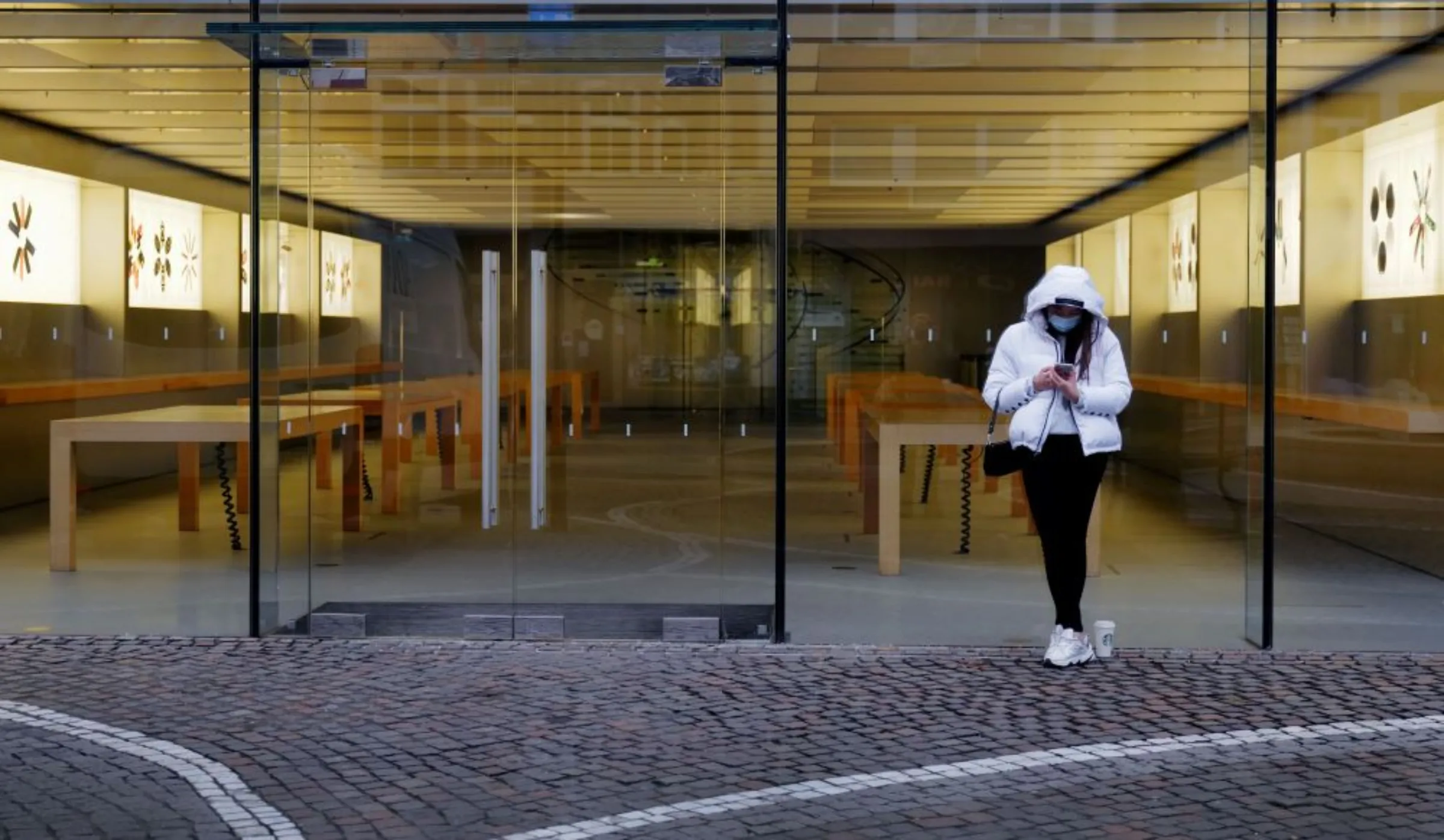 A girl checks her mobile phone as she stands in front of an empty Apple store during an extended lockdown as the spread of the coronavirus disease (COVID-19) continues in Frankfurt, Germany, January 21, 2021. REUTERS/Kai Pfaffenbach