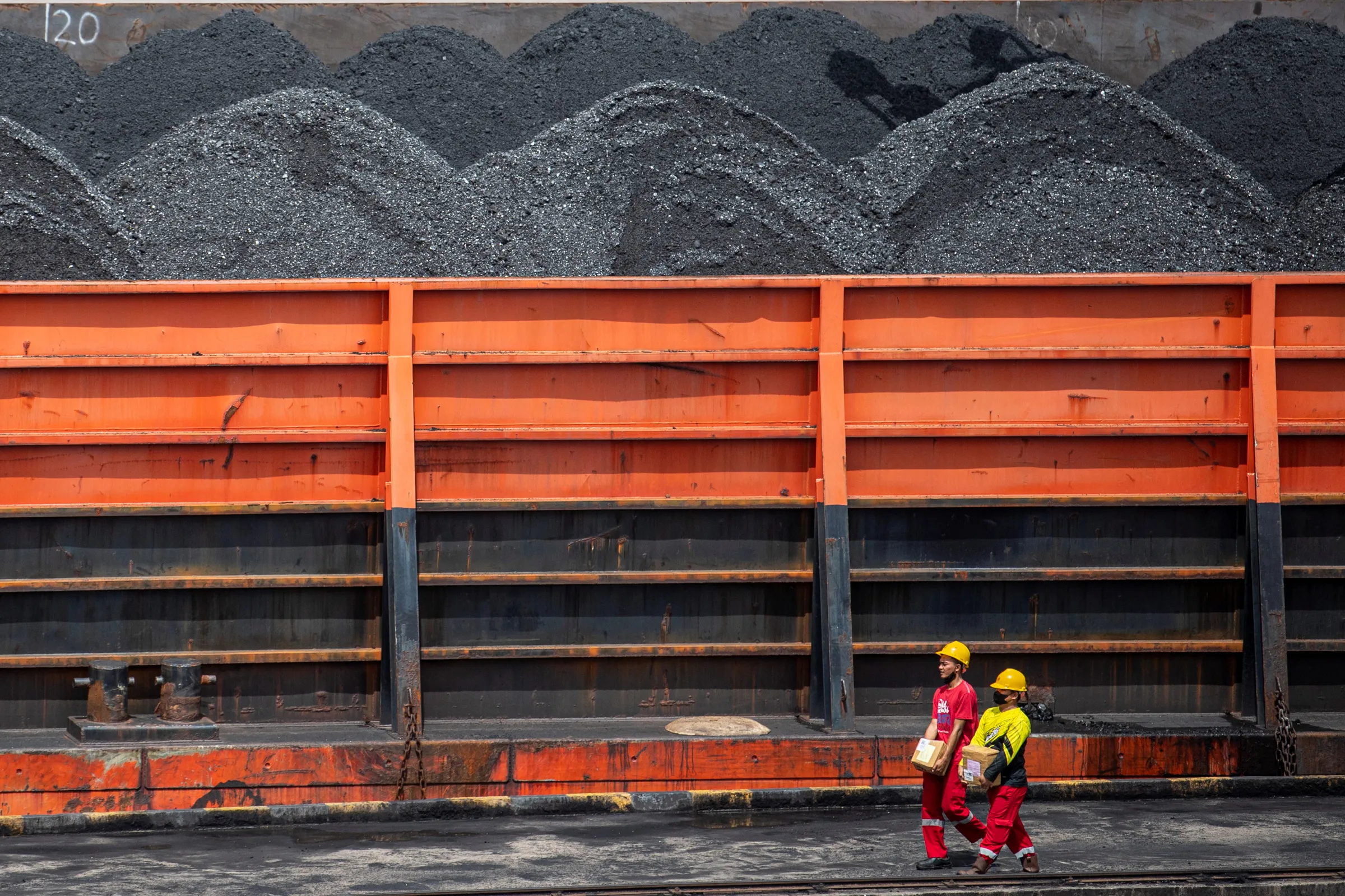 Workers walk near a tugboat carrying coal barges at a port in Palembang, South Sumatra province, Indonesia, January 4, 2022, in this photo taken by Antara Foto. Antara Foto/Nova Wahyudi/ via REUTERS v