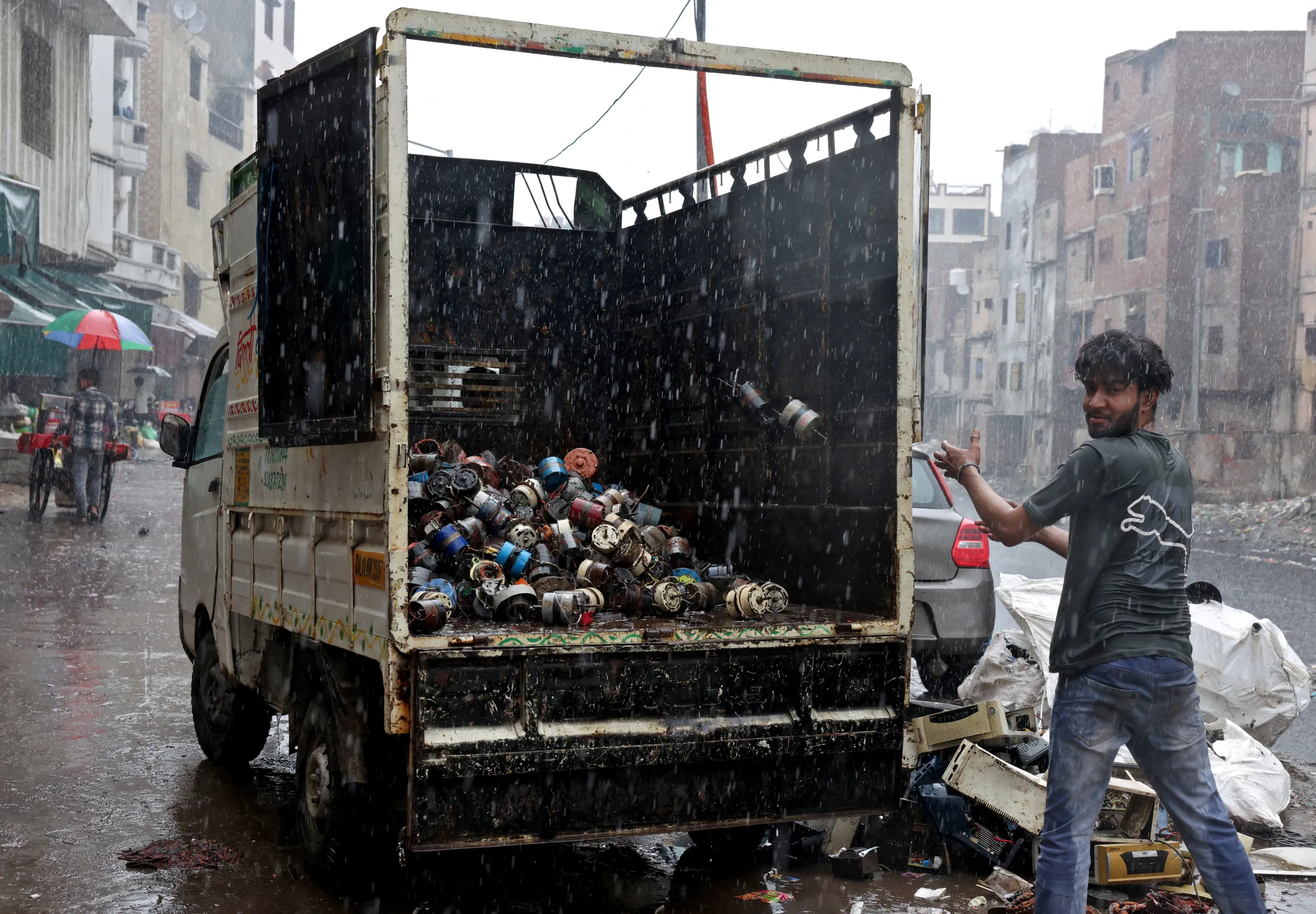 A worker at a scrap workshop loads a truck with old electric motors as it rains at an e-waste market in New Delhi, India, July 29, 2025.REUTERS/Bhawika Chhabra