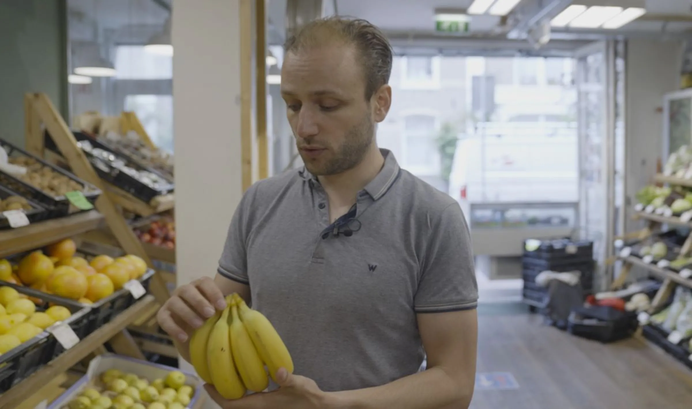 Michael Scholte, co-founder of True Price Initiative looks at bananas in his hand as he walks around a supermarket in Amsterdam, in this still from the video 'This grocery store wants to fix capitalism'. Albert Han/Thomson Reuters Foundation