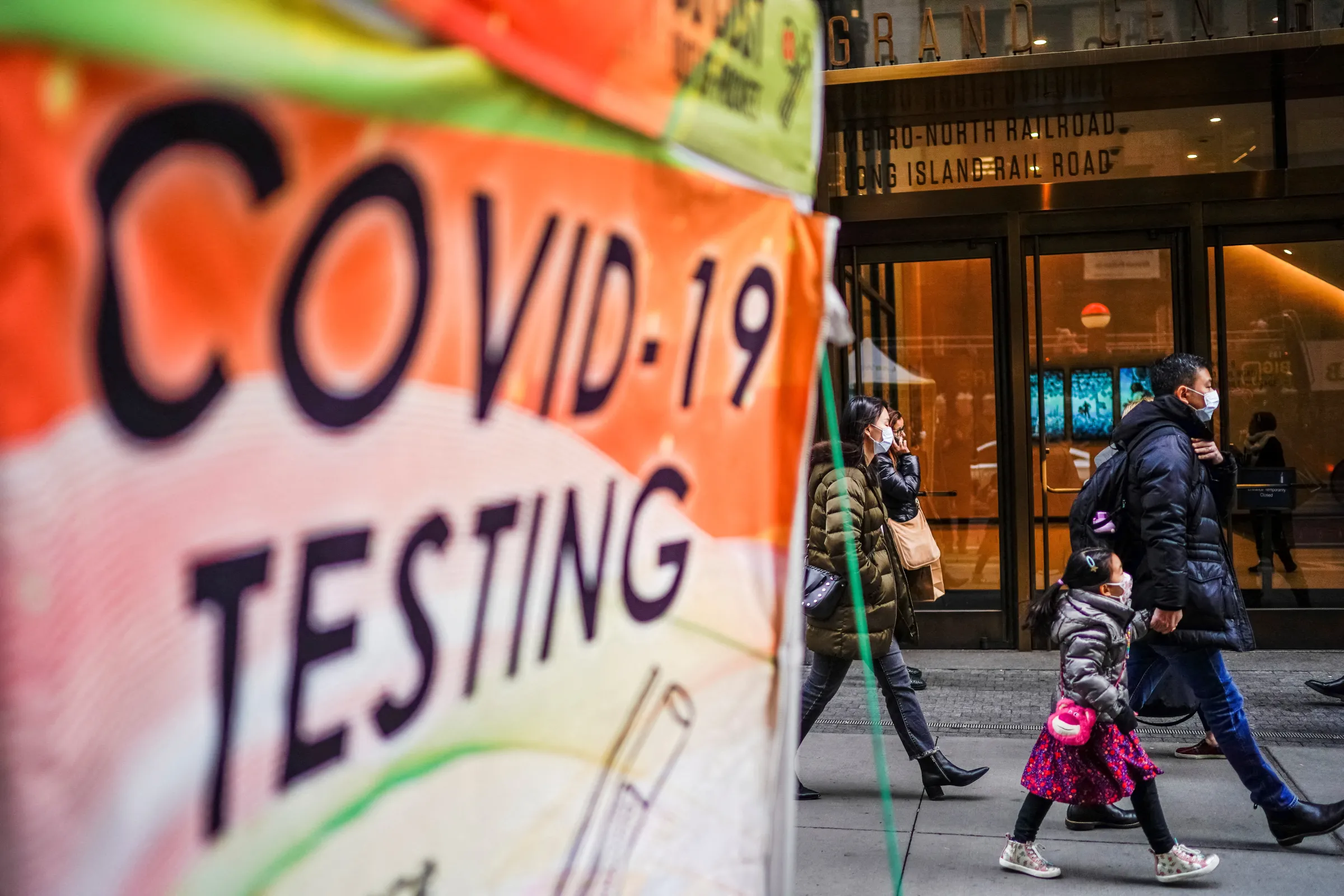 People wearing masks walk next to coronavirus disease (COVID-19) testing site in New York City, New York, U.S., December 12, 2022. REUTERS/Eduardo Munoz